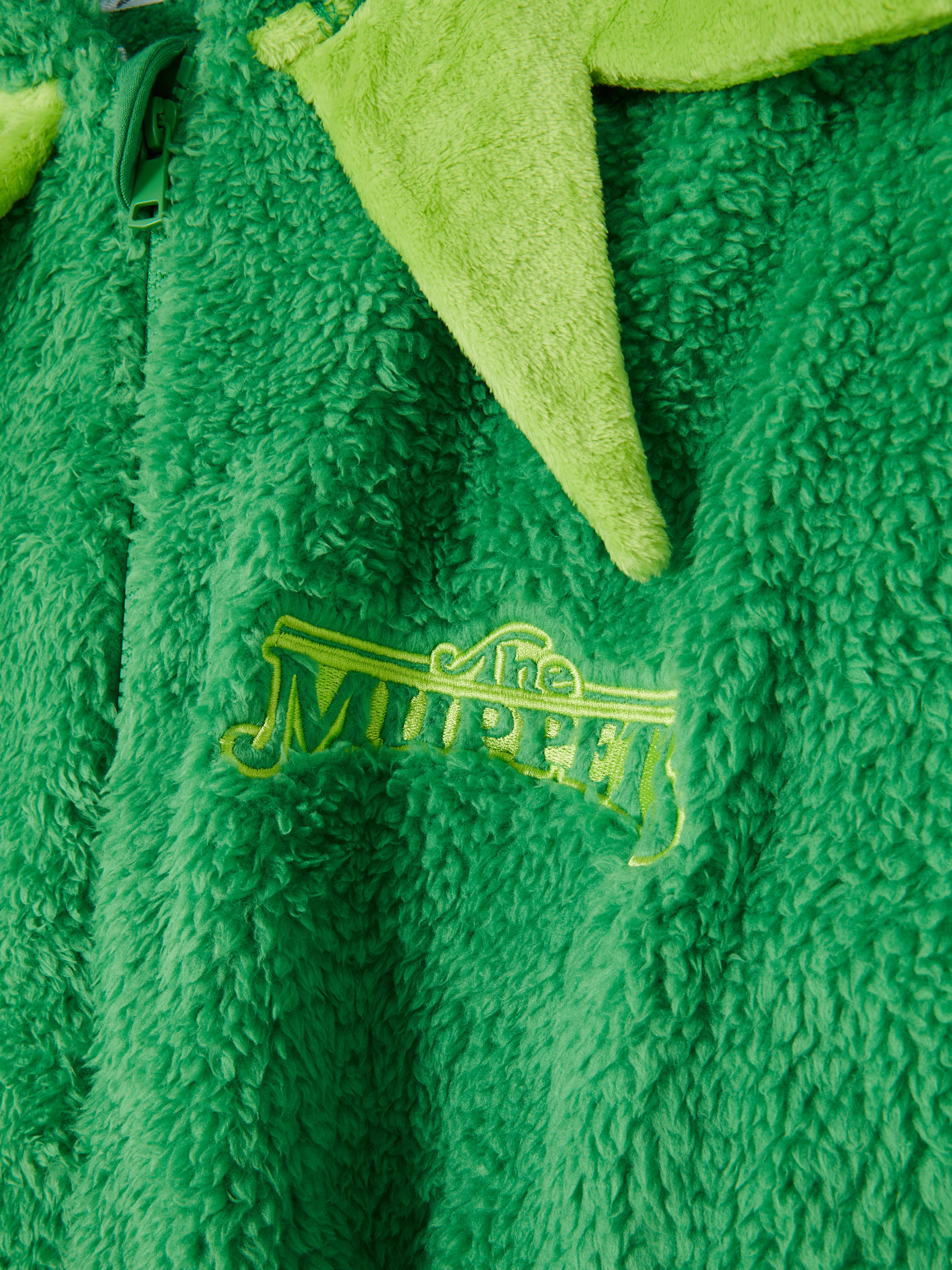 Salopetă din fleece pentru femei cu personajele Muppets, cu glugă, închidere cu fermoar și manșete cu nervuri.