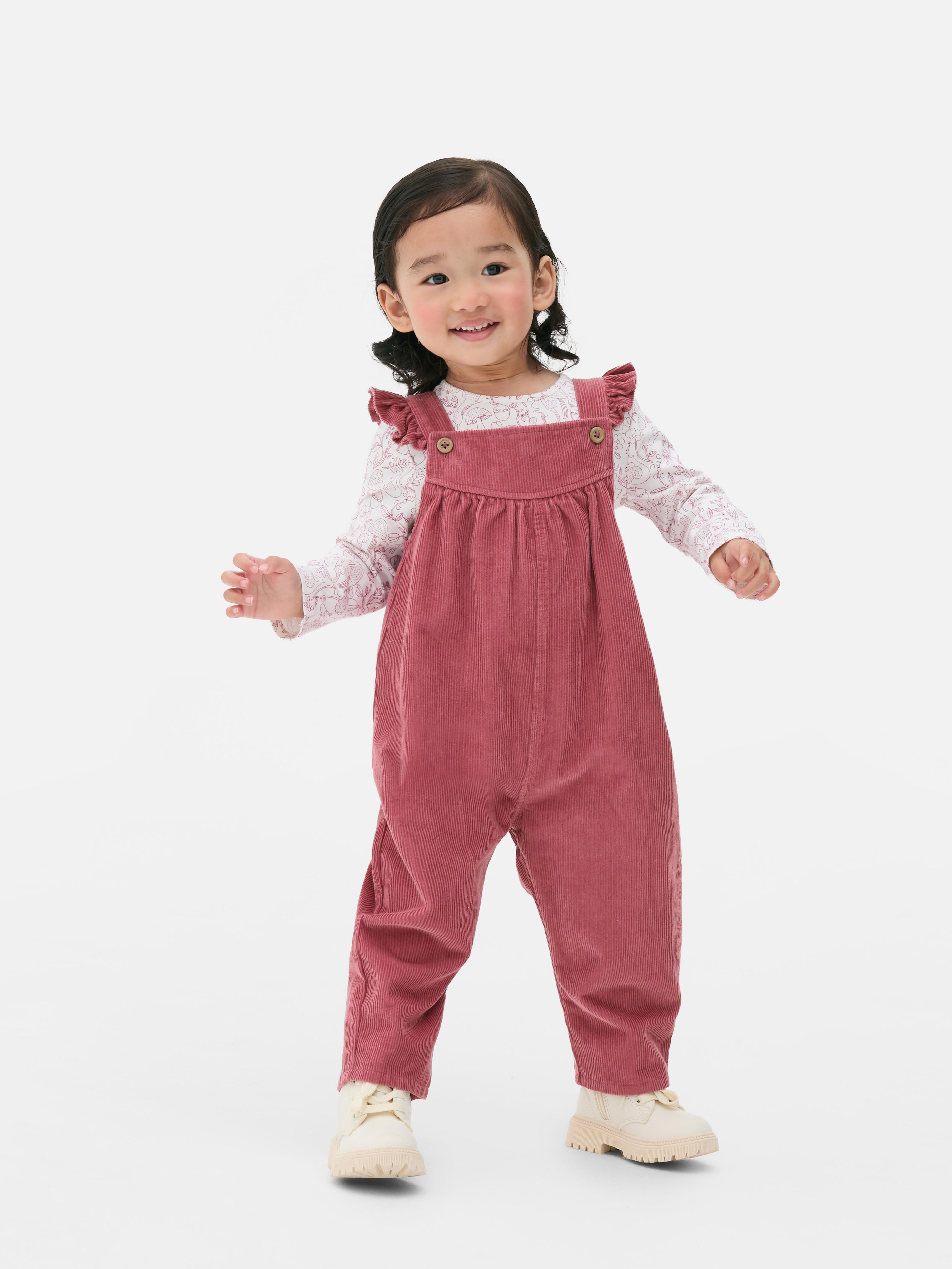 Set format din tricou cu mânecă lungă și salopetă. Un tricou cu mânecă lungă cu model și salopetă din catifea reiată.
