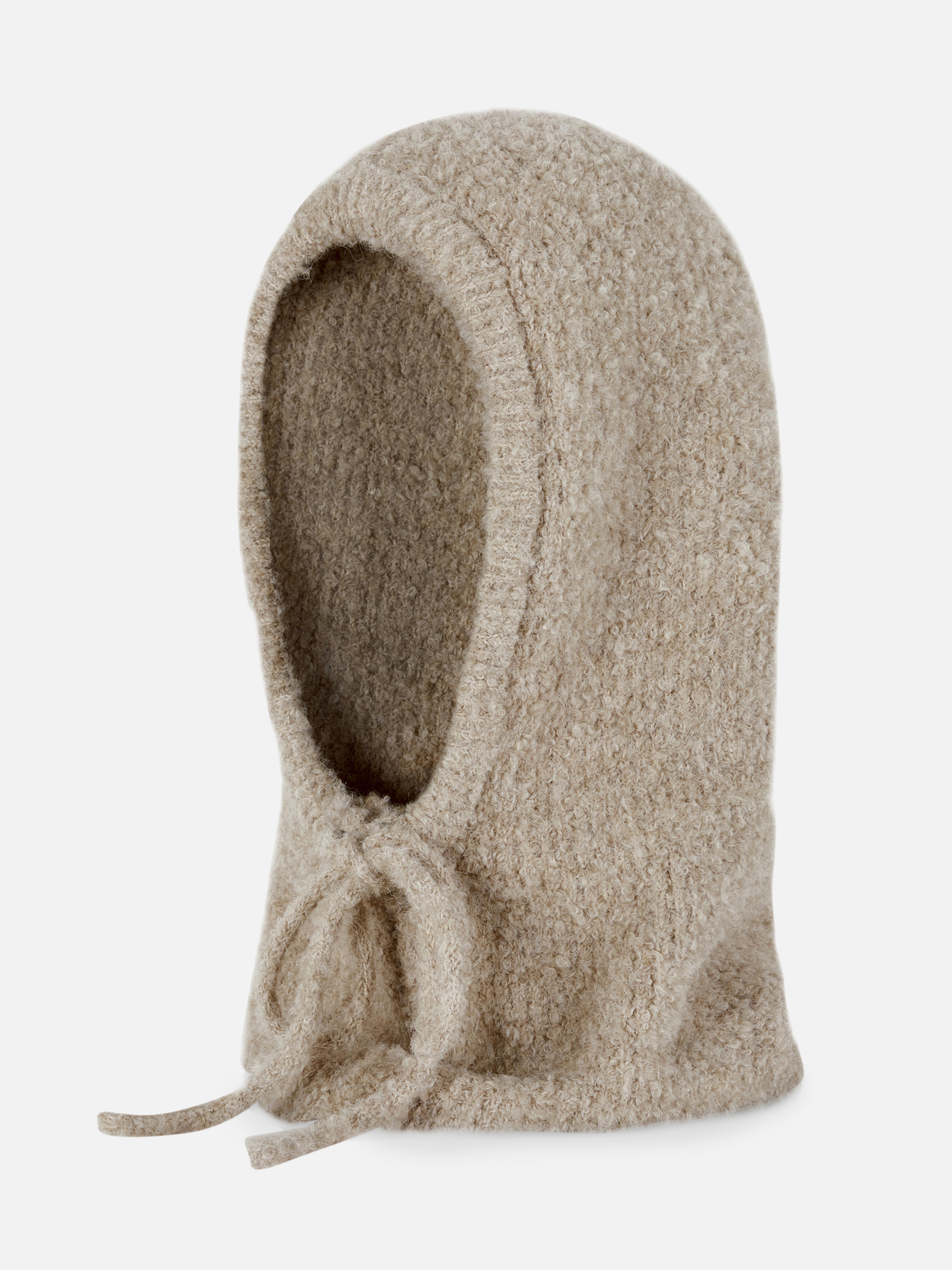Glugă din material bouclé cu șnur în față. O glugă moale și călduroasă, confecționată din material bouclé, cu închidere cu șnur în față.