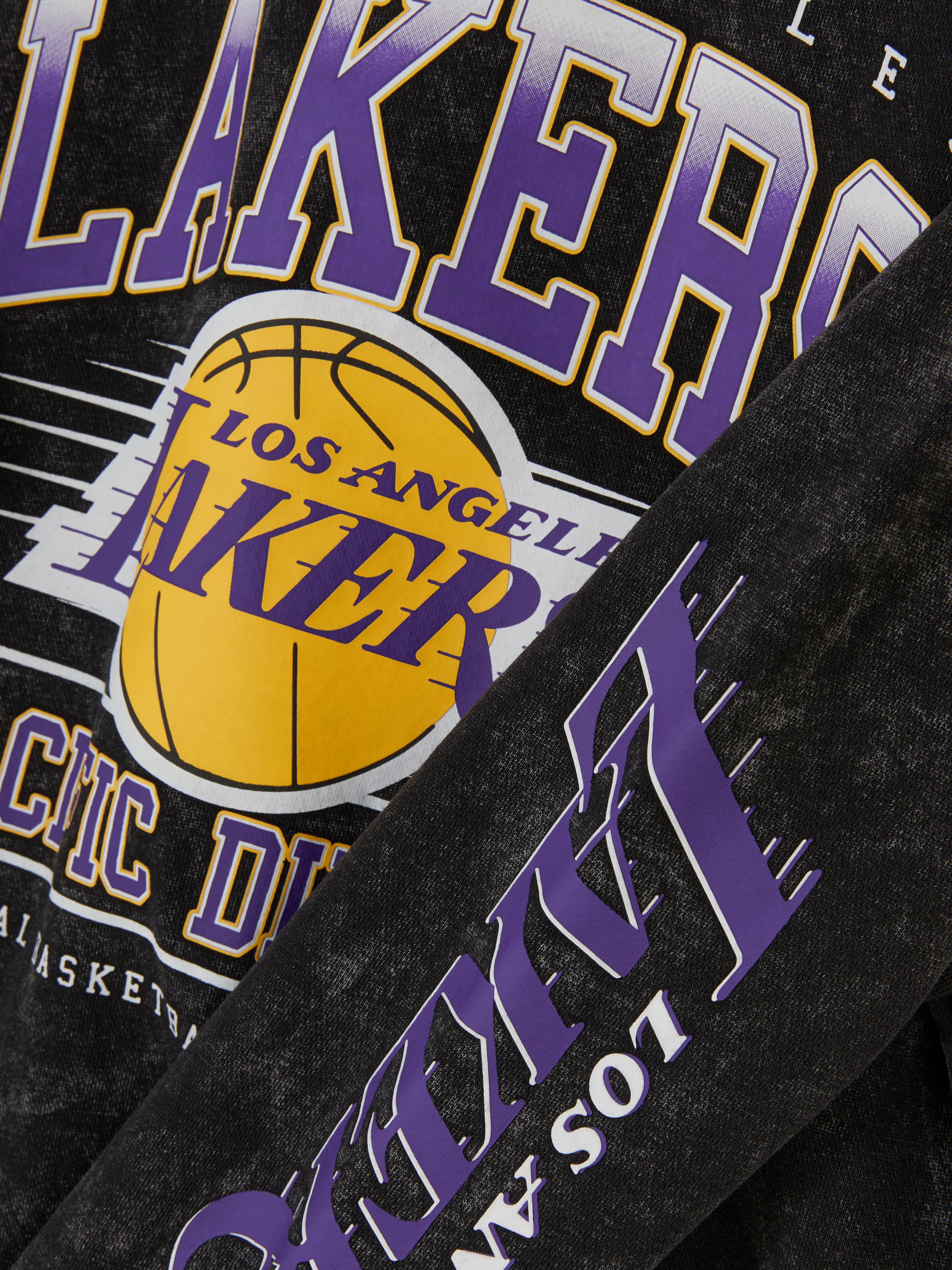 NBA Los Angeles Lakers pulóver savas mosással. Egy csapatpulóver ejtett vállal, Los Angeles Lakers emblémákkal és savas mosás hatású megjelenéssel.