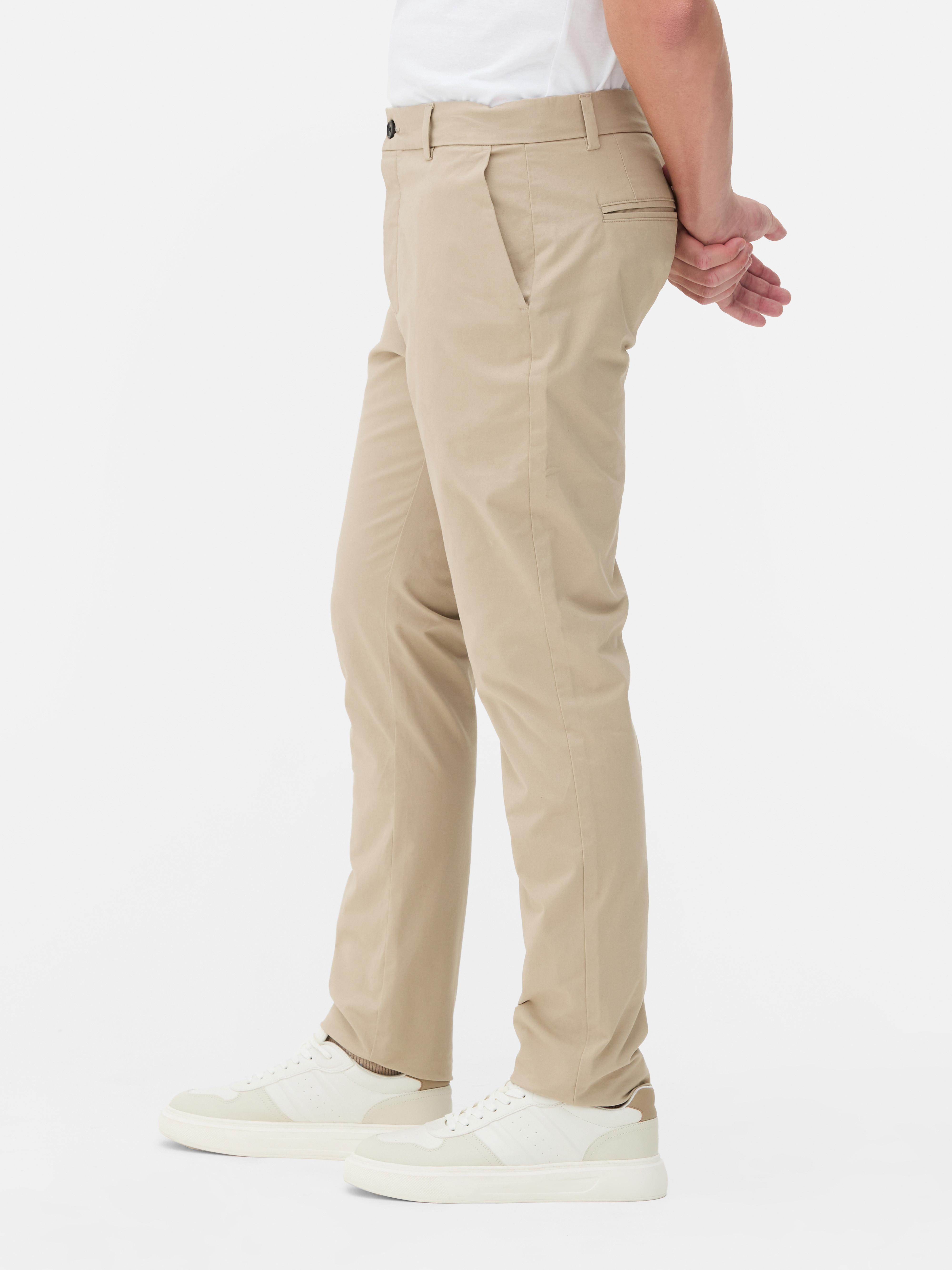 Pantaloni chino elastici, mulați. Pantaloni chino mulați, confecționați în principal din bumbac și cu buzunare laterale.