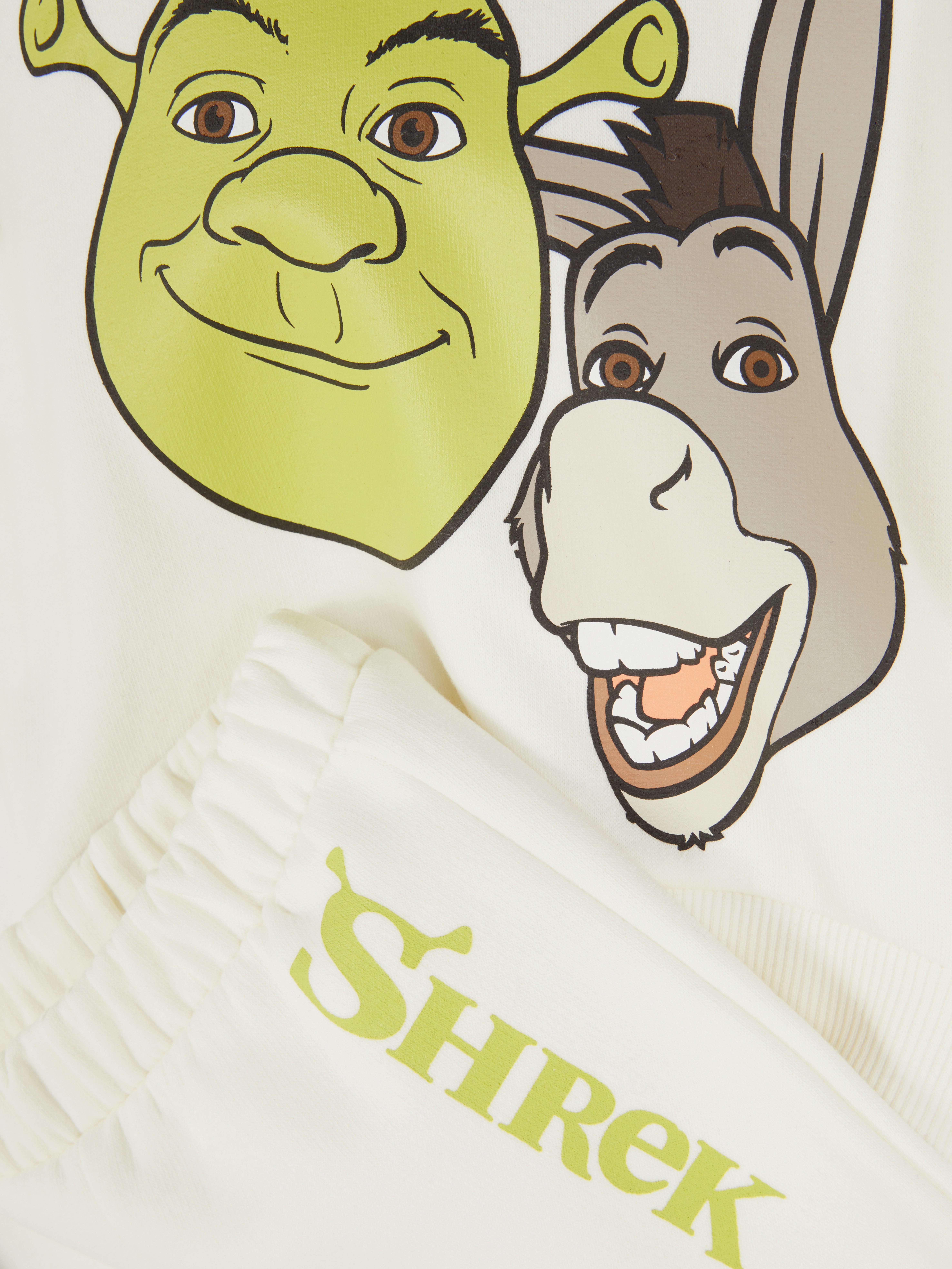 Hanorac și pantaloni de trening asortați cu tematică Shrek. Un hanorac cu tematică Shrek și pantaloni de trening asortați cu manșete la gleznă.