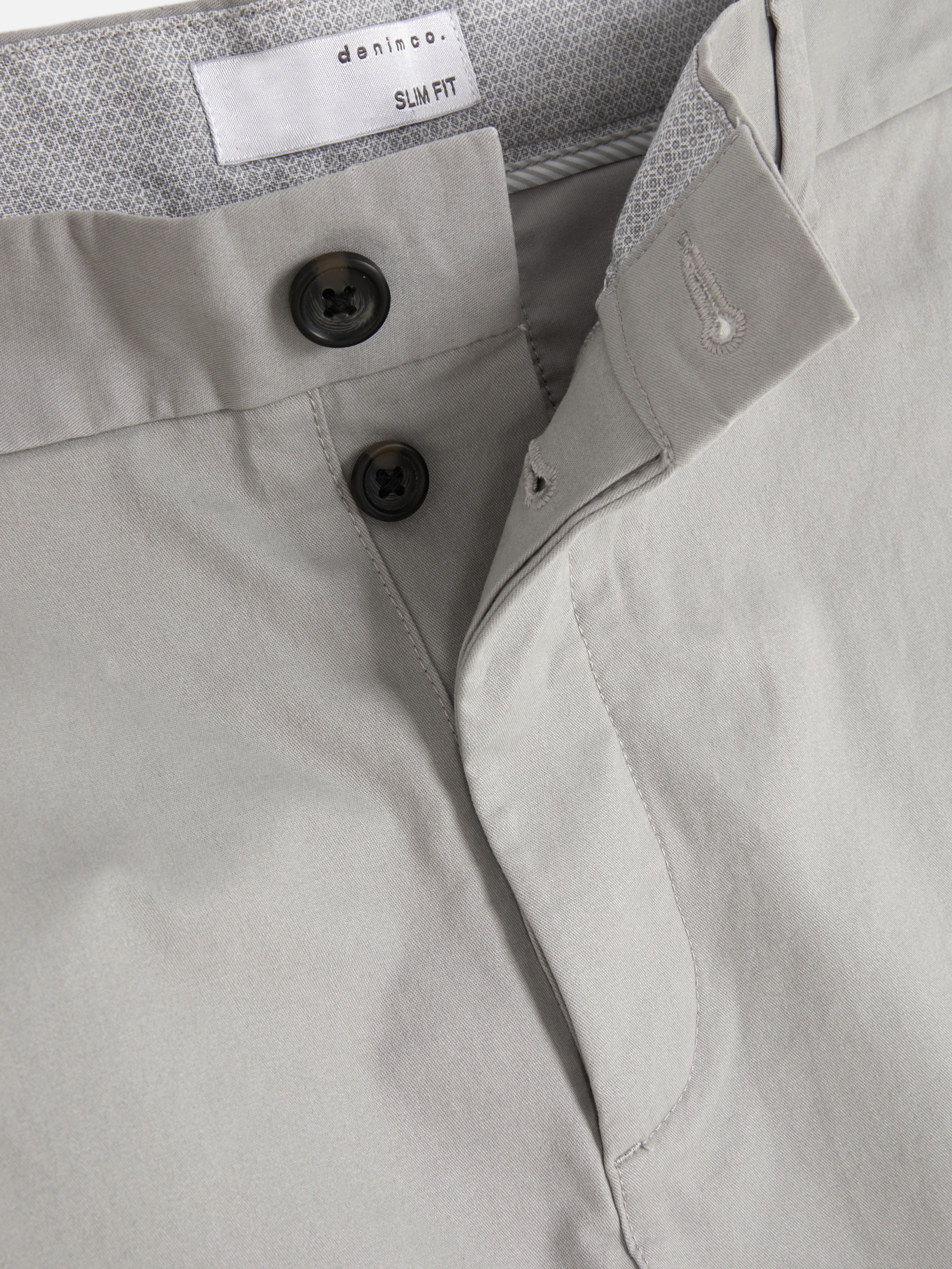 Pantaloni chino elastici, mulați. Pantaloni chino mulați, confecționați în principal din bumbac și cu buzunare laterale.