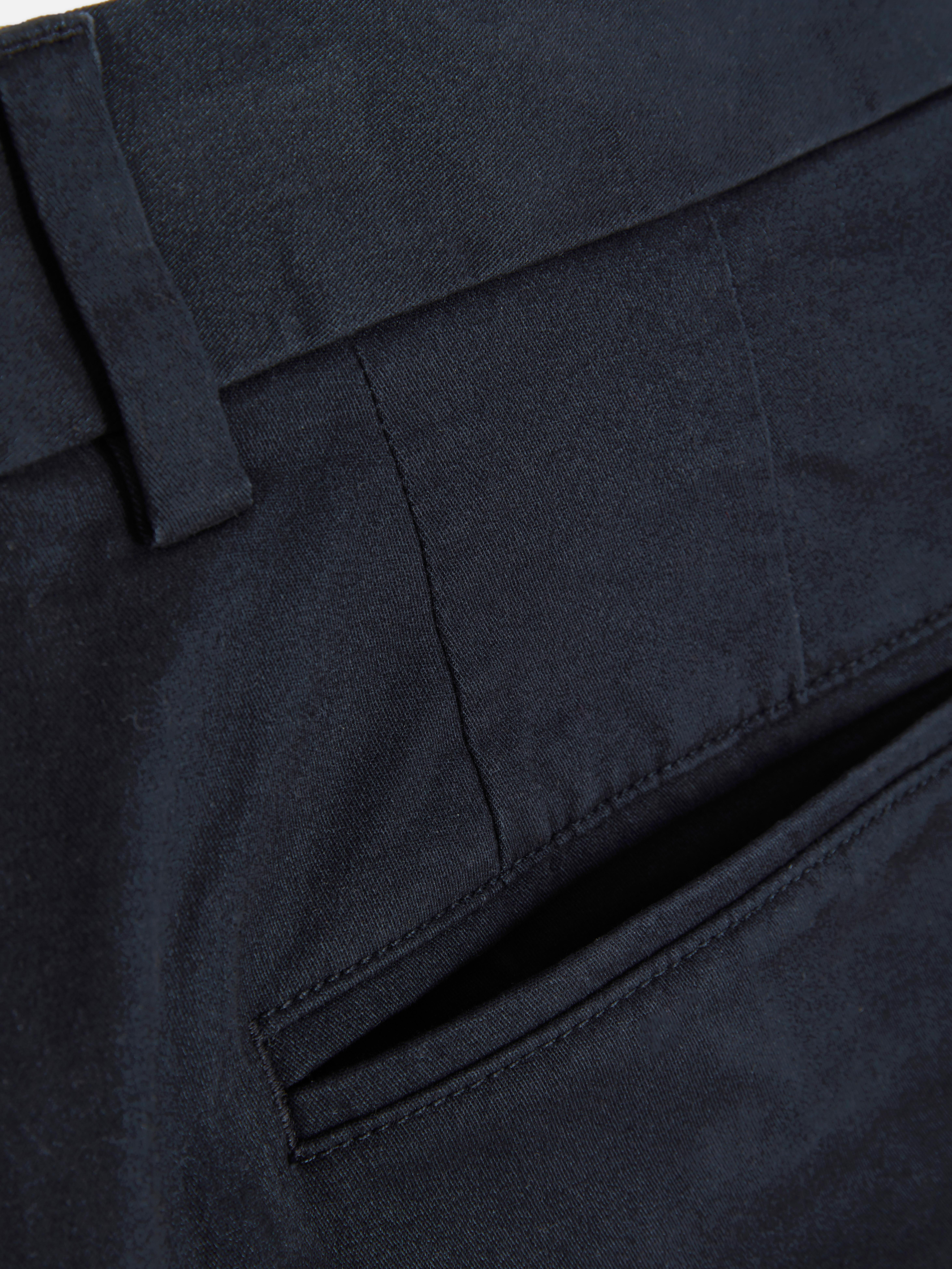 Pantaloni chino elastici, mulați. Pantaloni chino mulați, confecționați în principal din bumbac și cu buzunare laterale.
