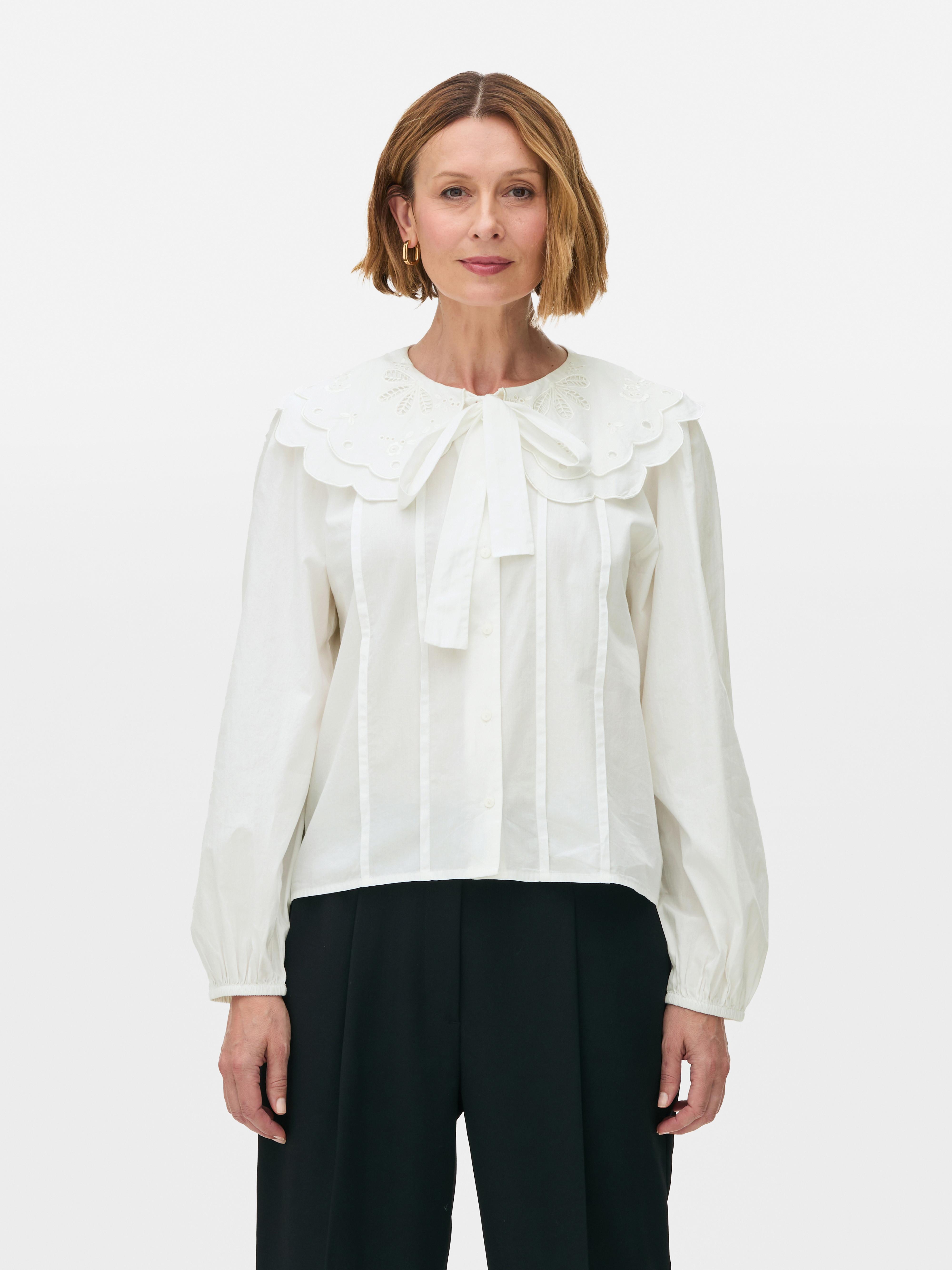 Blouse à col et découpes. Le col Claudine festonné, les empiècements et les manches bouffantes caractérisent cette blouse.
