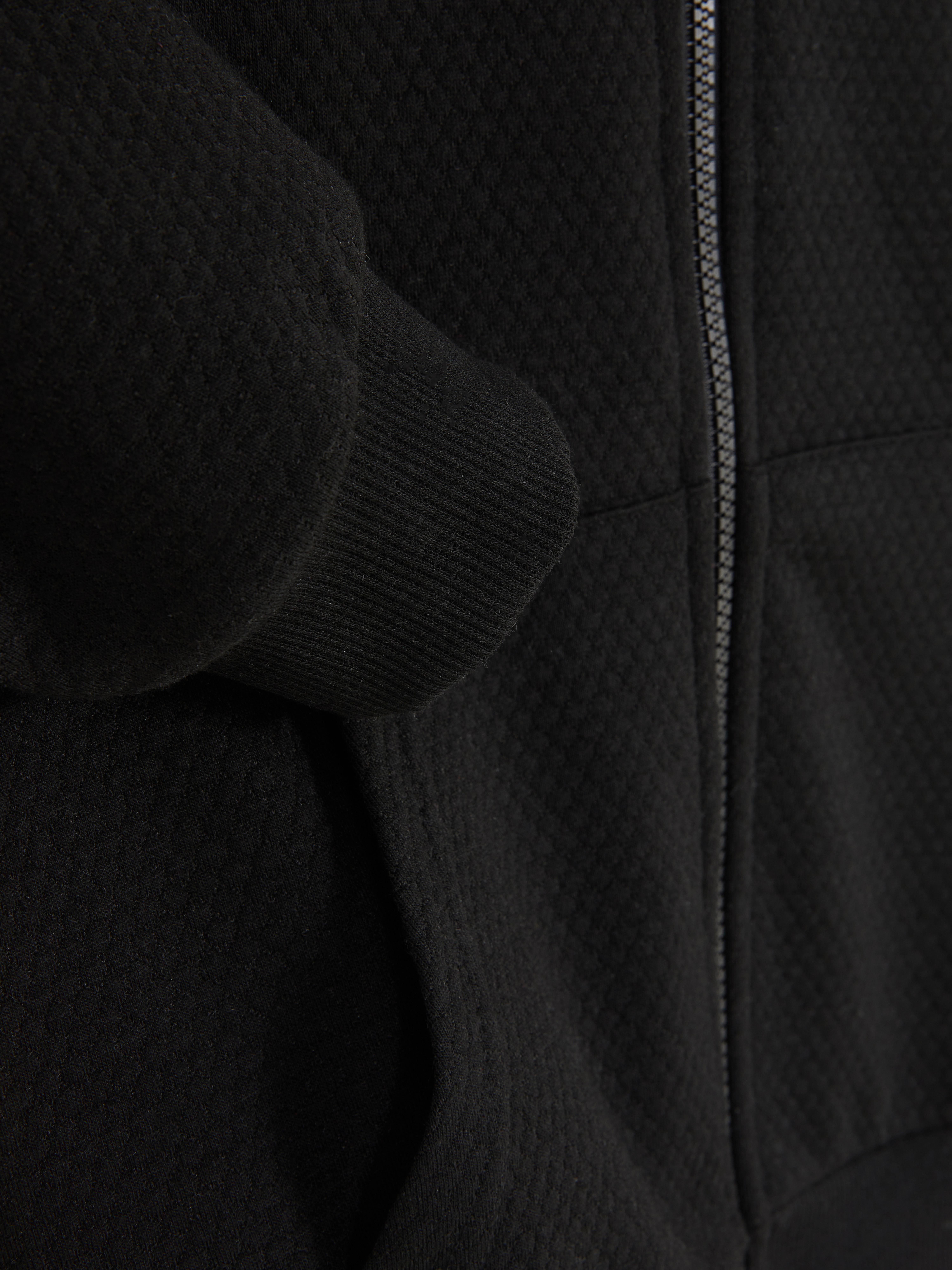 Strukturierter Hoodie mit Reißverschluss. Ein Hoodie mit Frontreißverschluss, langen Ärmeln mit Bündchen, Kängurutaschen und einem strukturierten Stoff.