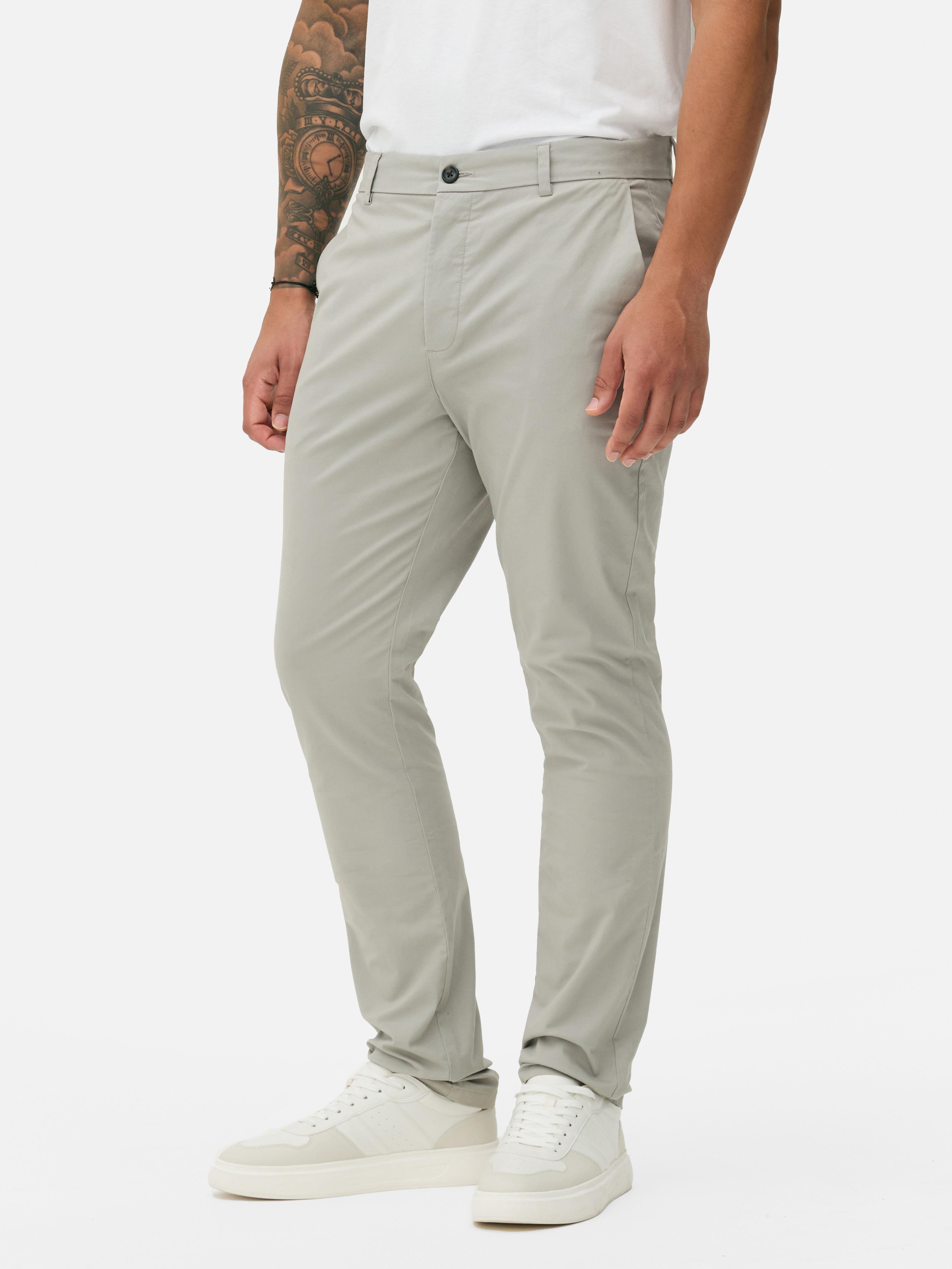 Pantaloni chino elastici, mulați. Pantaloni chino mulați, confecționați în principal din bumbac și cu buzunare laterale.
