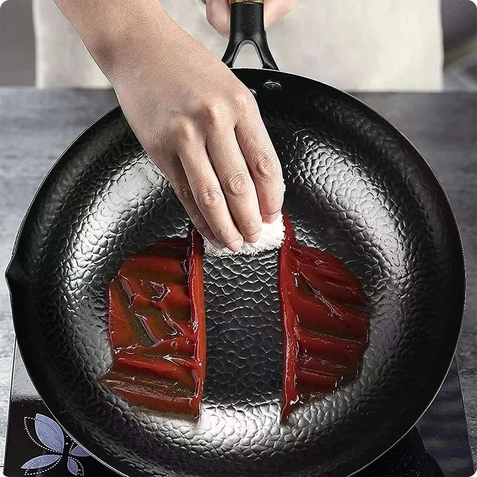 Poêle wok antiadhésive de 28 cm en fonte, non revêtue, idéale pour la cuisson des steaks, des crêpes et autres préparations culinaires. Fabriquée à la main, elle est compatible avec les plaques à gaz et à induction.