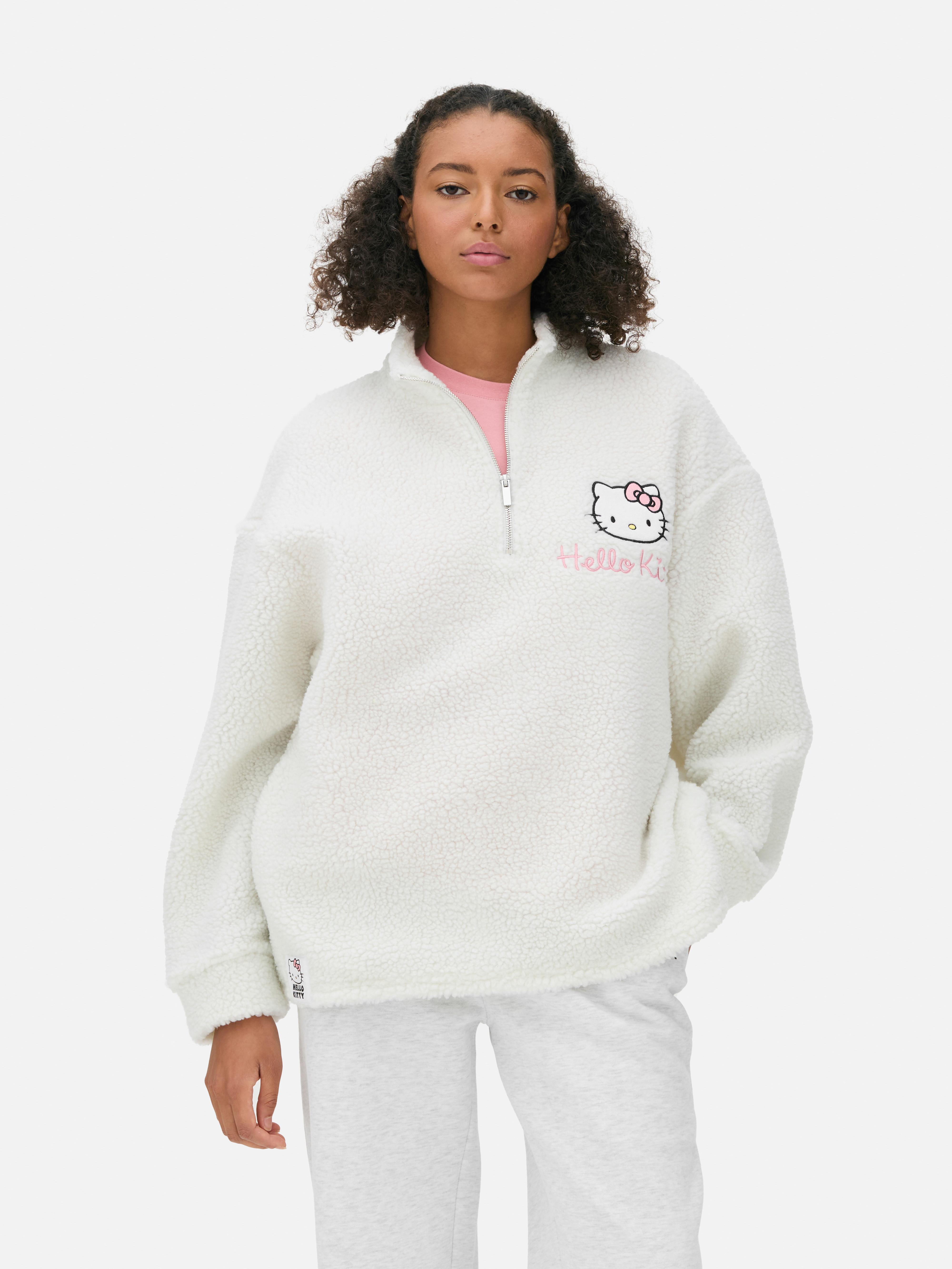 Hanorac din material textil Borg cu fermoar pe un sfert cu Hello Kitty. Acest hanorac din fleece cu fermoar pe un sfert și imprimeu Hello Kitty are o notă nostalgică.
