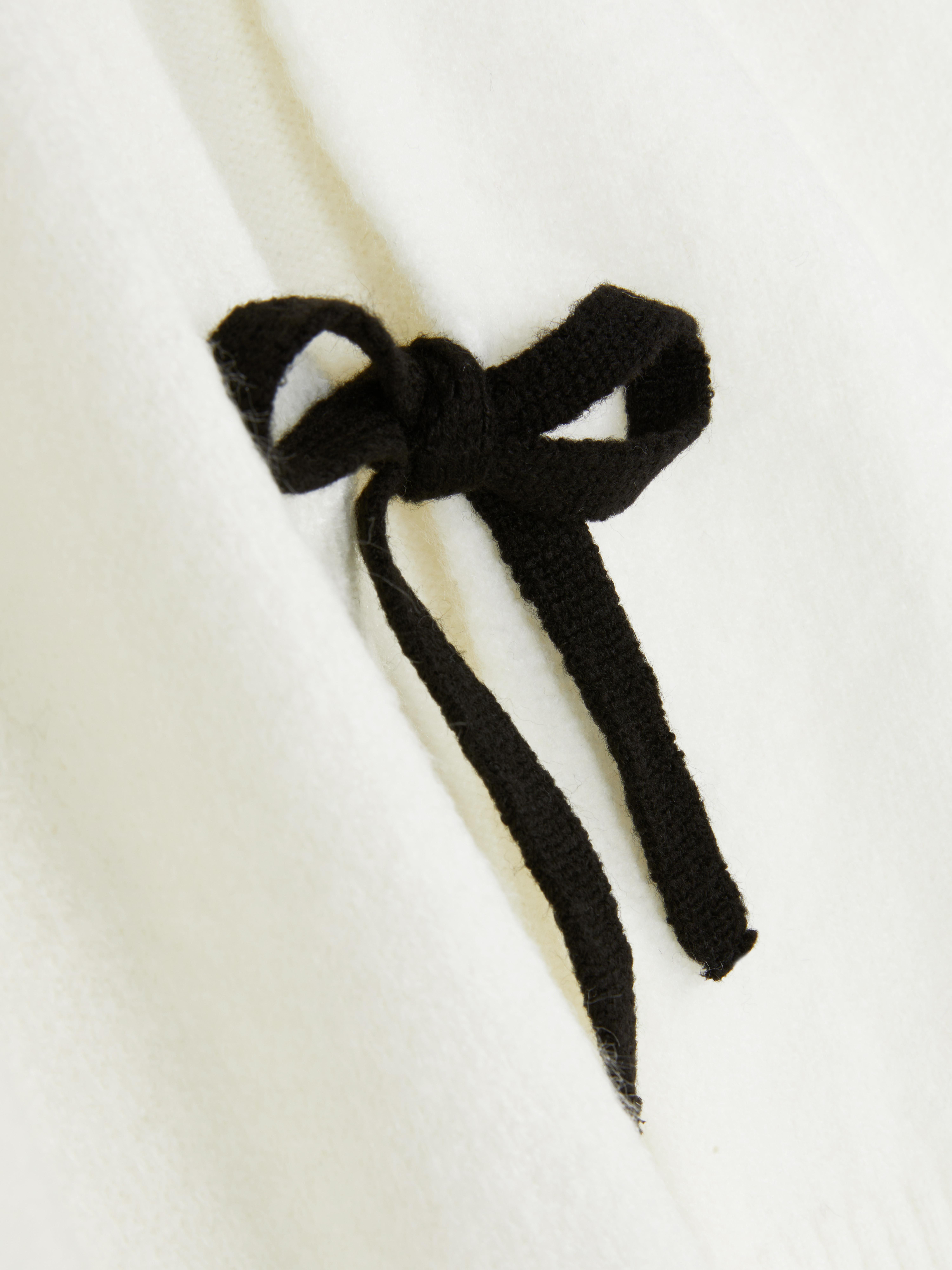 Cardigan med knyting foran En strikket cardigan med ribbede mansjetter og knyting