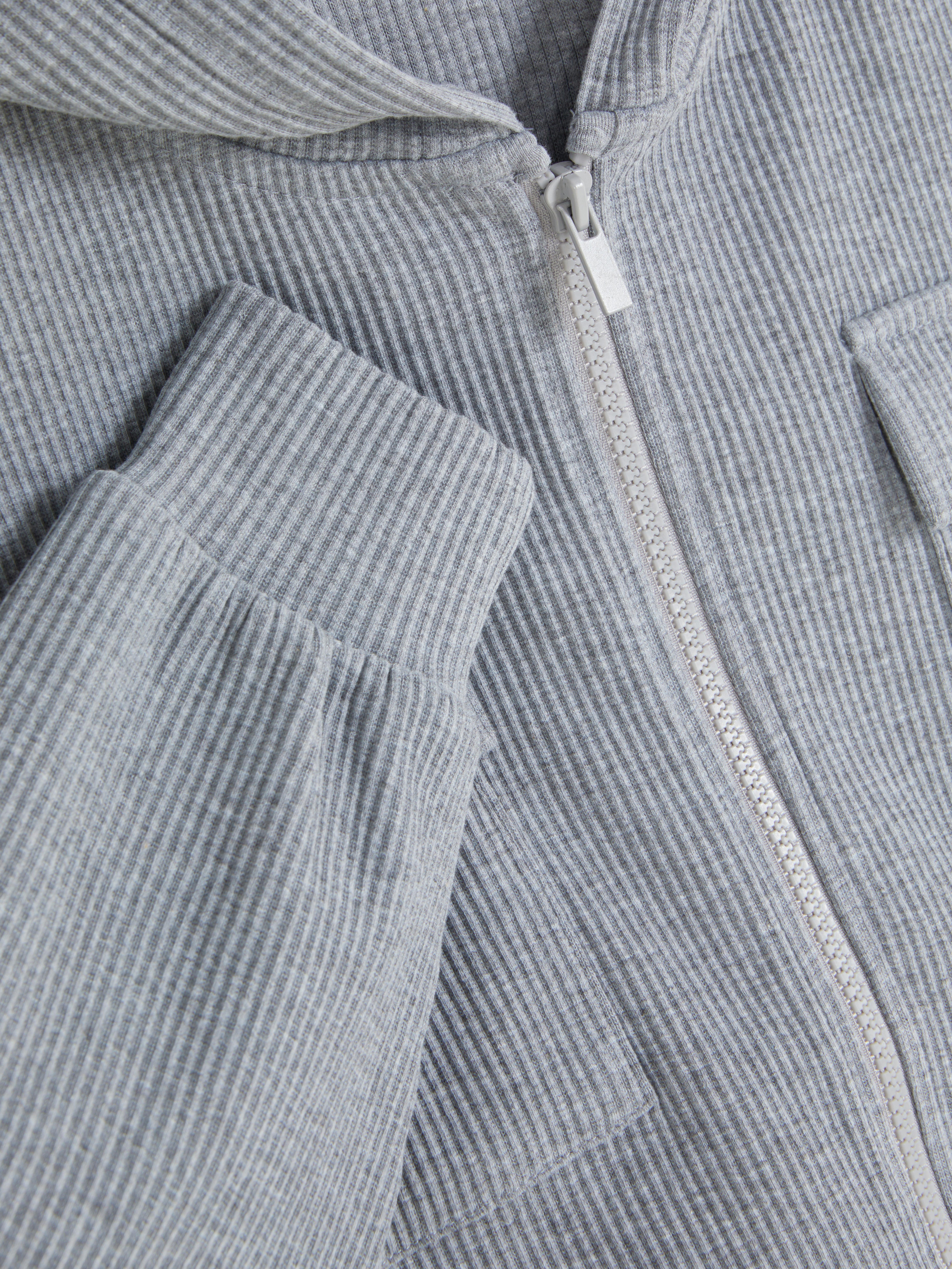 Passender gerippter Hoodie mit Reißverschluss. Ein gerippter Langarm-Hoodie mit Bündchen, Brusttaschen und Frontreißverschluss.