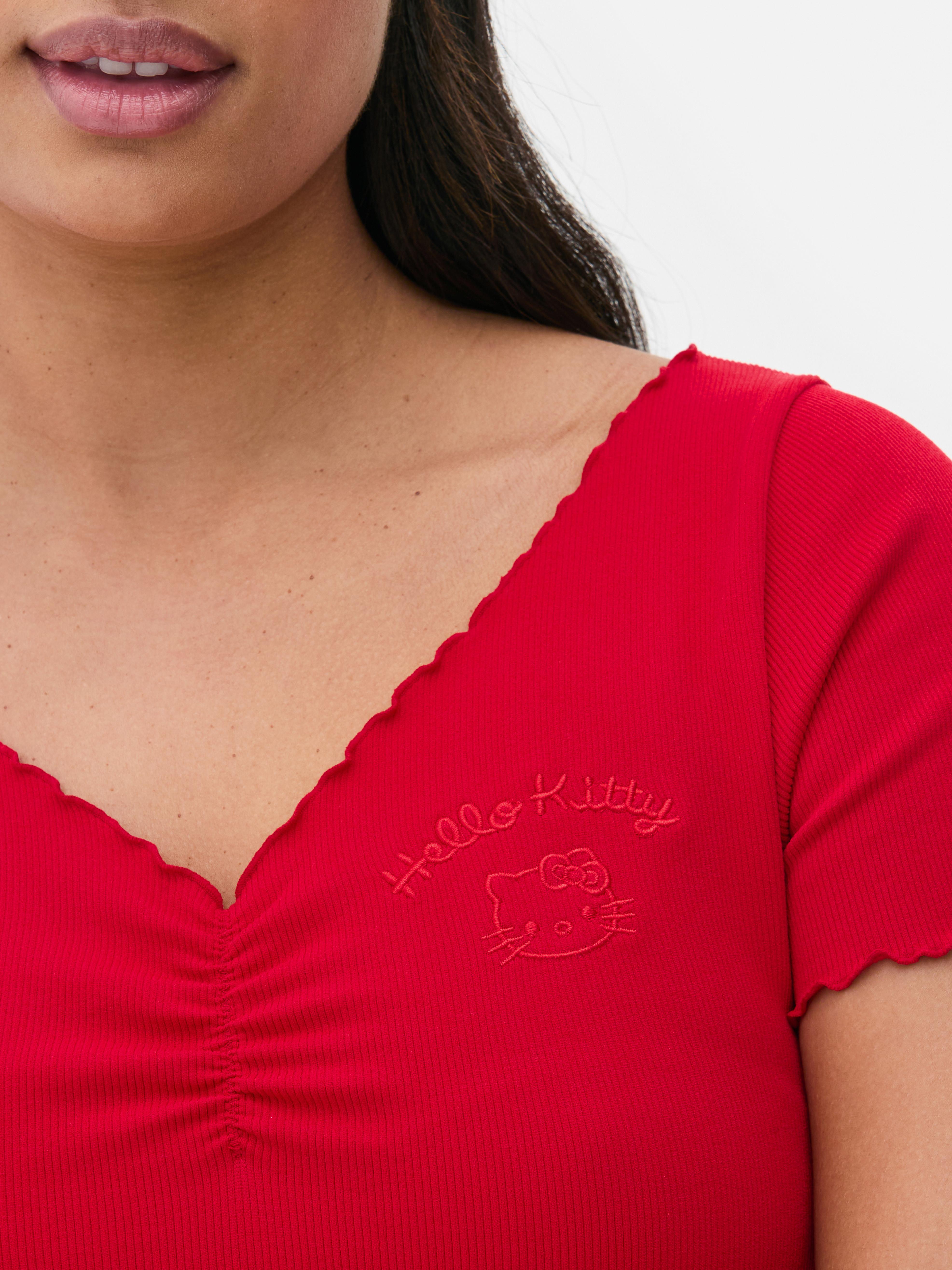 Tricou scurt Hello Kitty Un tricou scurt cu imprimeu Hello Kitty, decolteu în V și tiv festonat