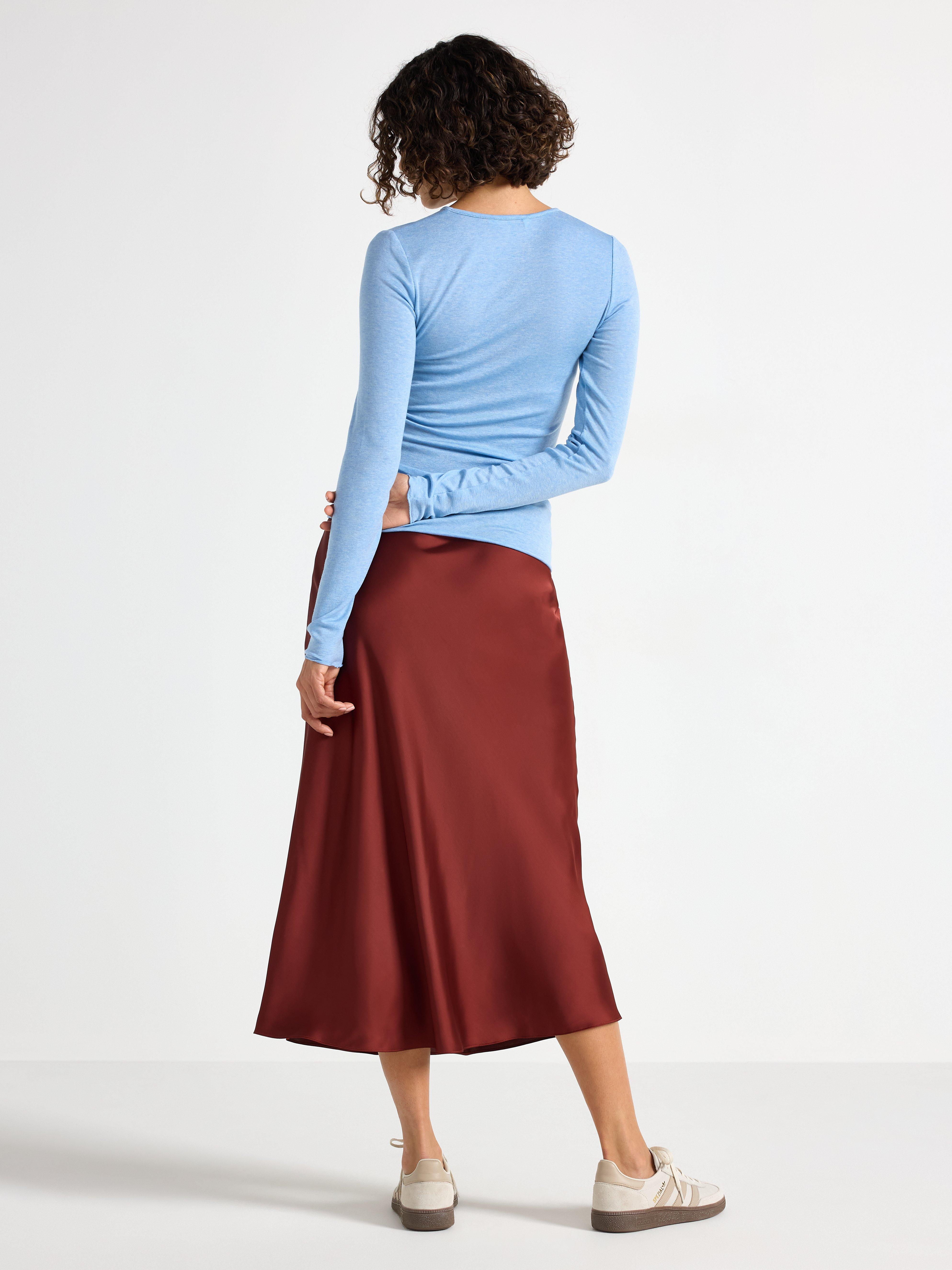 Falda midi de satén color rojo oscuro empolvado.