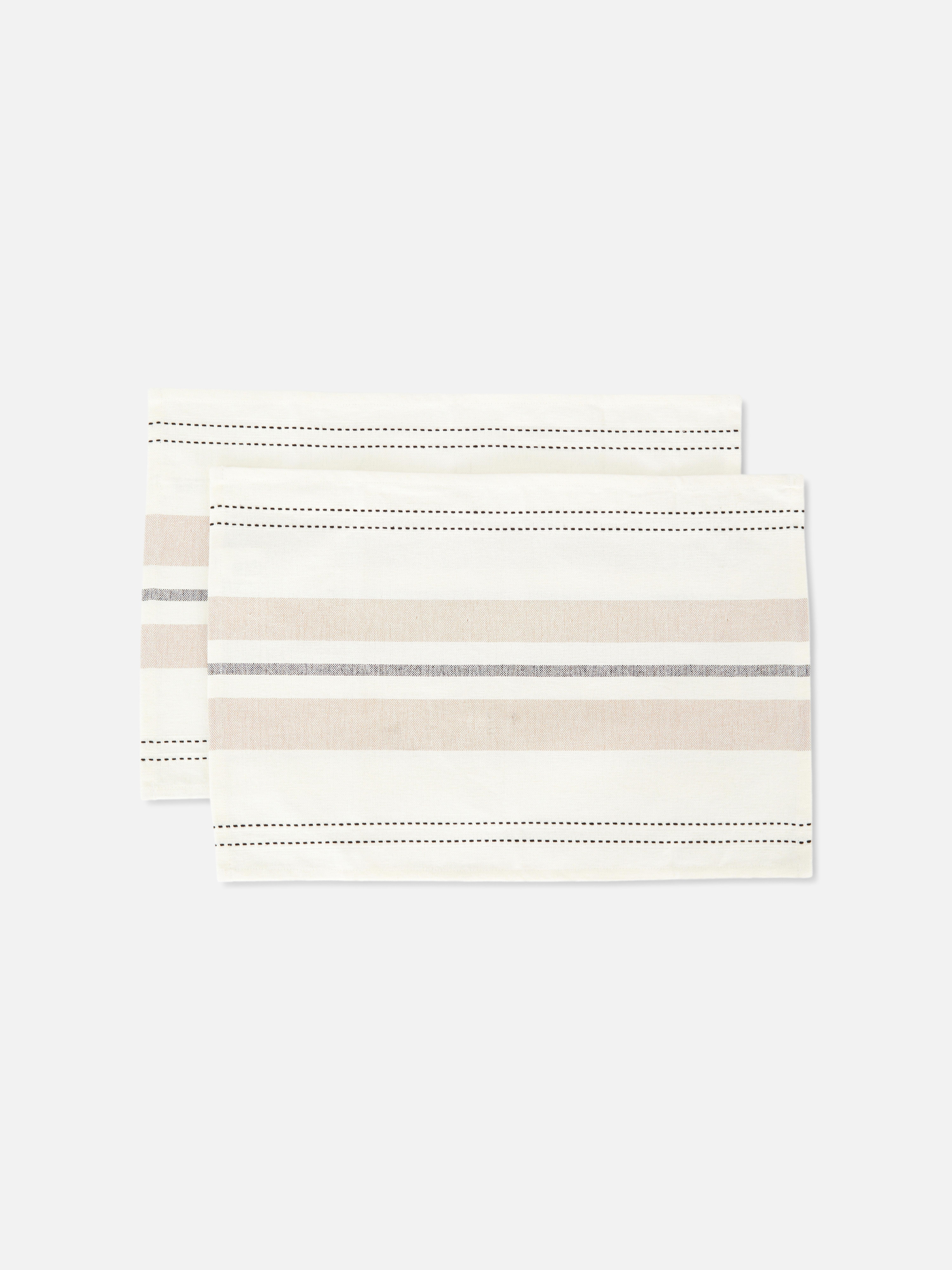 Gestreifte Stoff-Platzsets, 2er-Set. Diese eleganten, gestreiften Platzsets in neutralen Tönen mit schwarzen Ziernähten verleihen Ihrer Tischdekoration eine besondere Note.