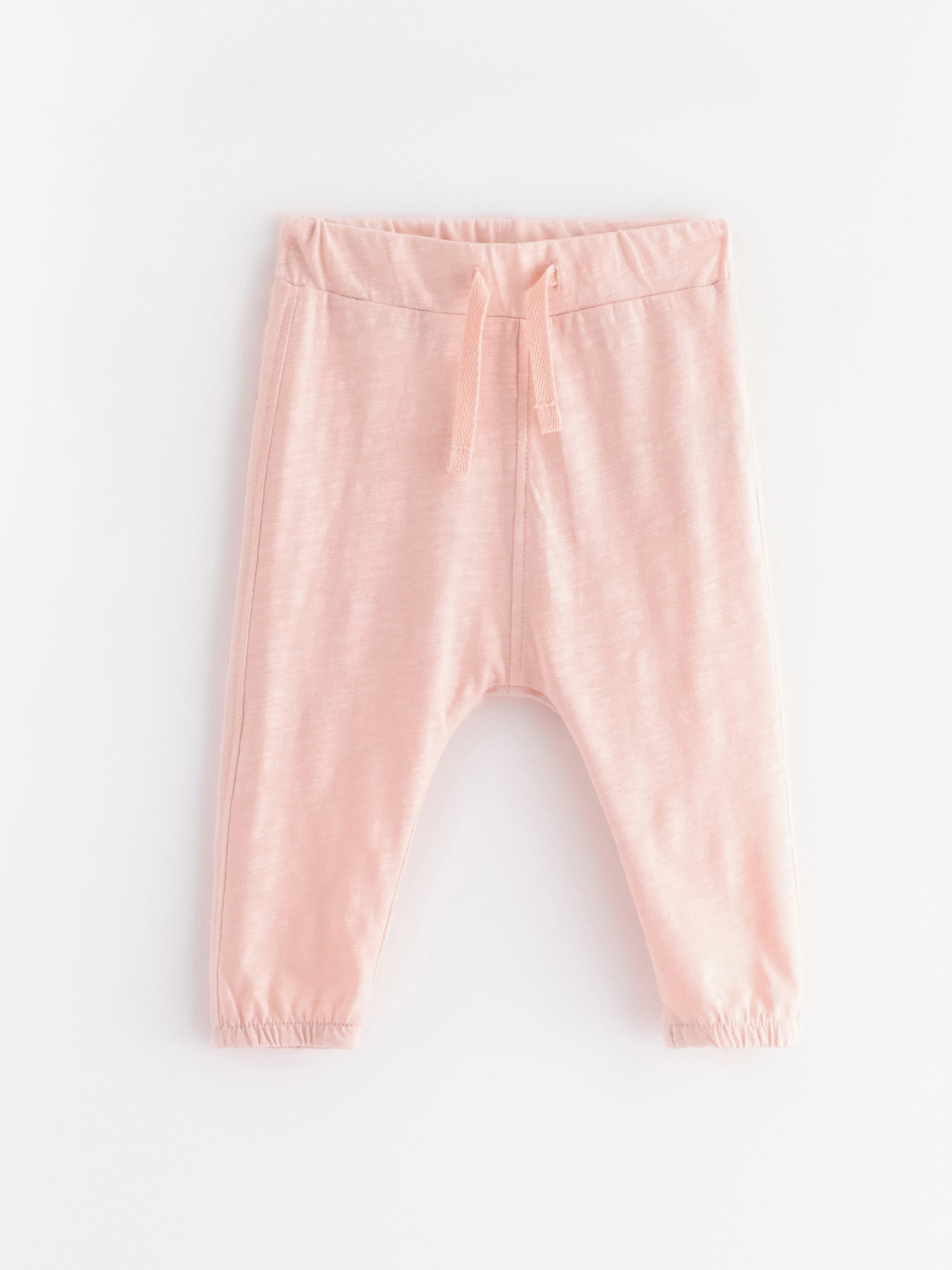 Pantalones deportivos de punto flameado, color rosa claro empolvado.