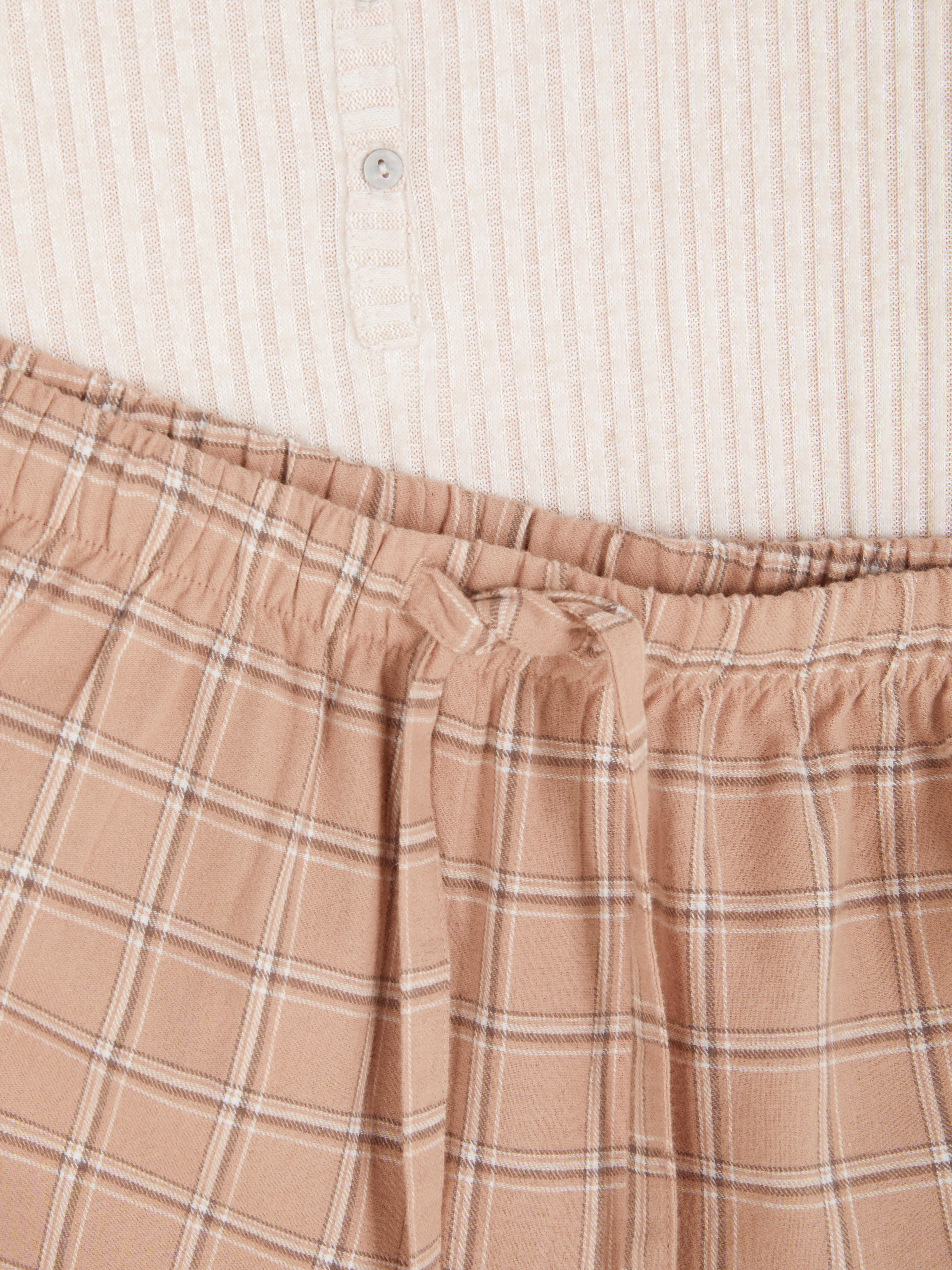 Pijamale cu pantaloni în carouri și o cămașă cu mânecă lungă. Aceste pijamale drăguțe și confortabile creează o atmosferă relaxantă.