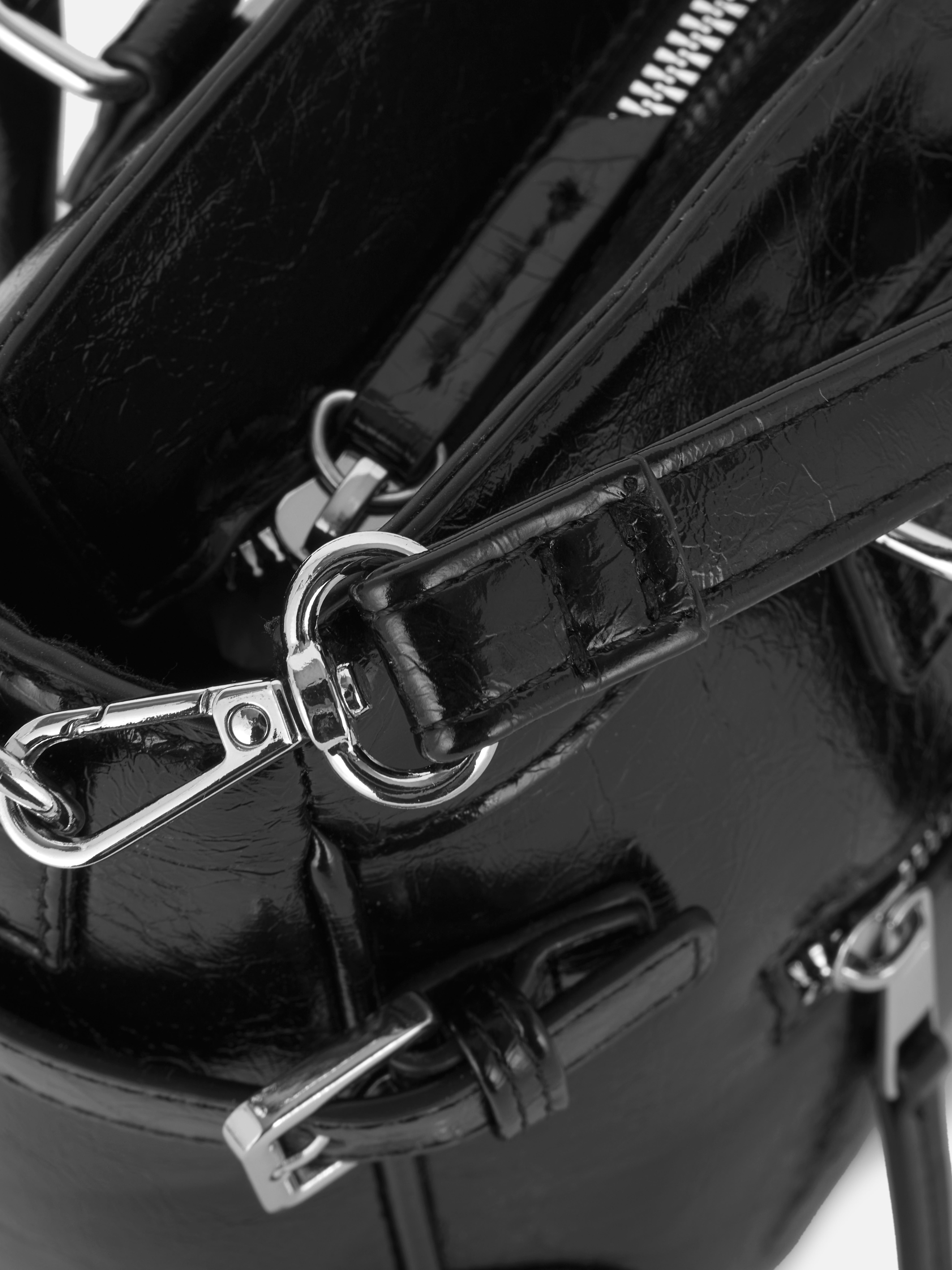 Abgenutzte Schultertasche aus Kunstleder. Eine mittellange Tragetasche aus Kunstleder mit Used-Look, mit Reißverschlusstaschen und Schnallendetails.