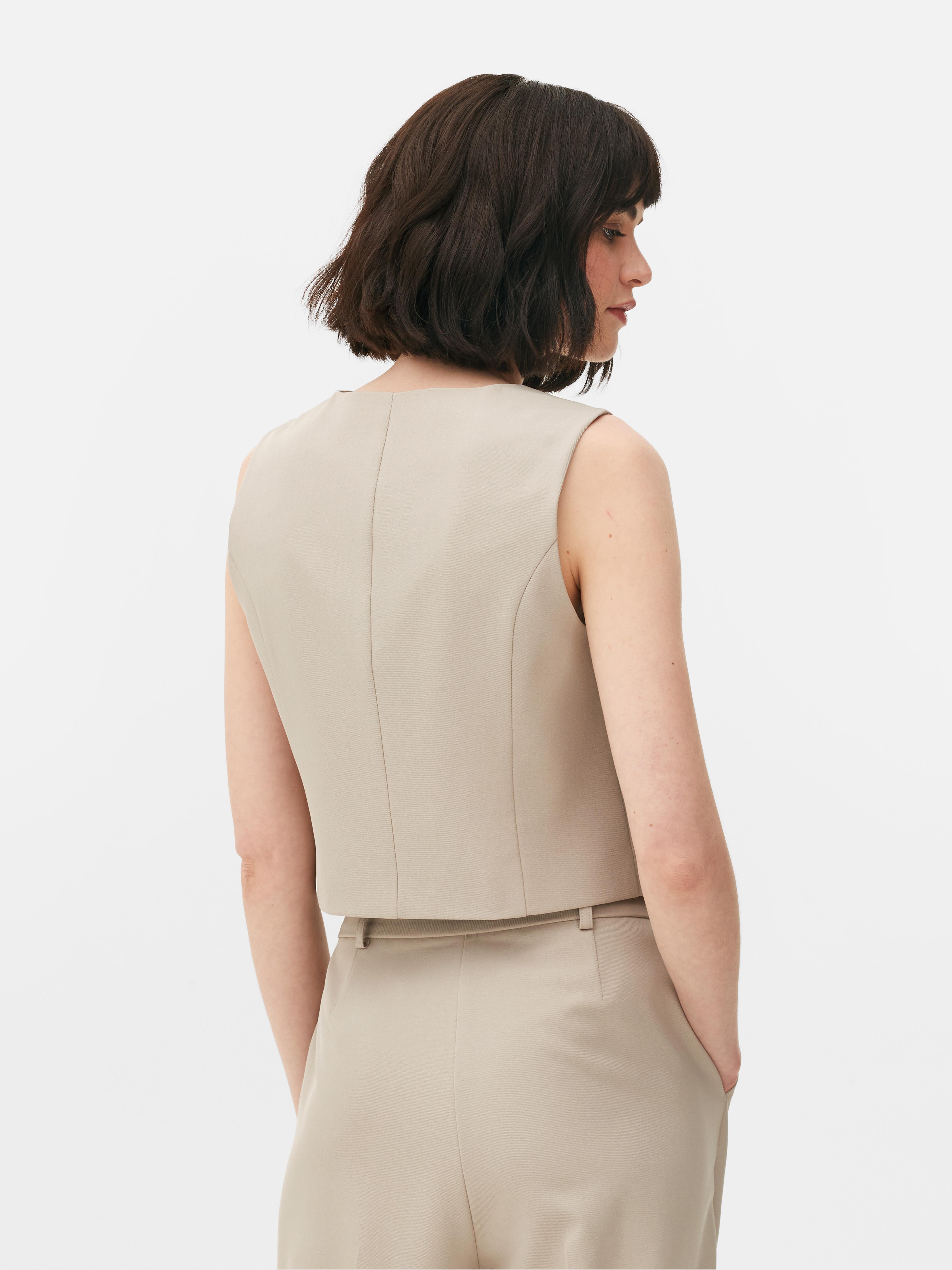 Vestă elegantă cu închidere cu nasturi. Această vestă atemporală, cu cusături prințesă, închidere cu nasturi și decolteu în V, este un adevărat must-have.