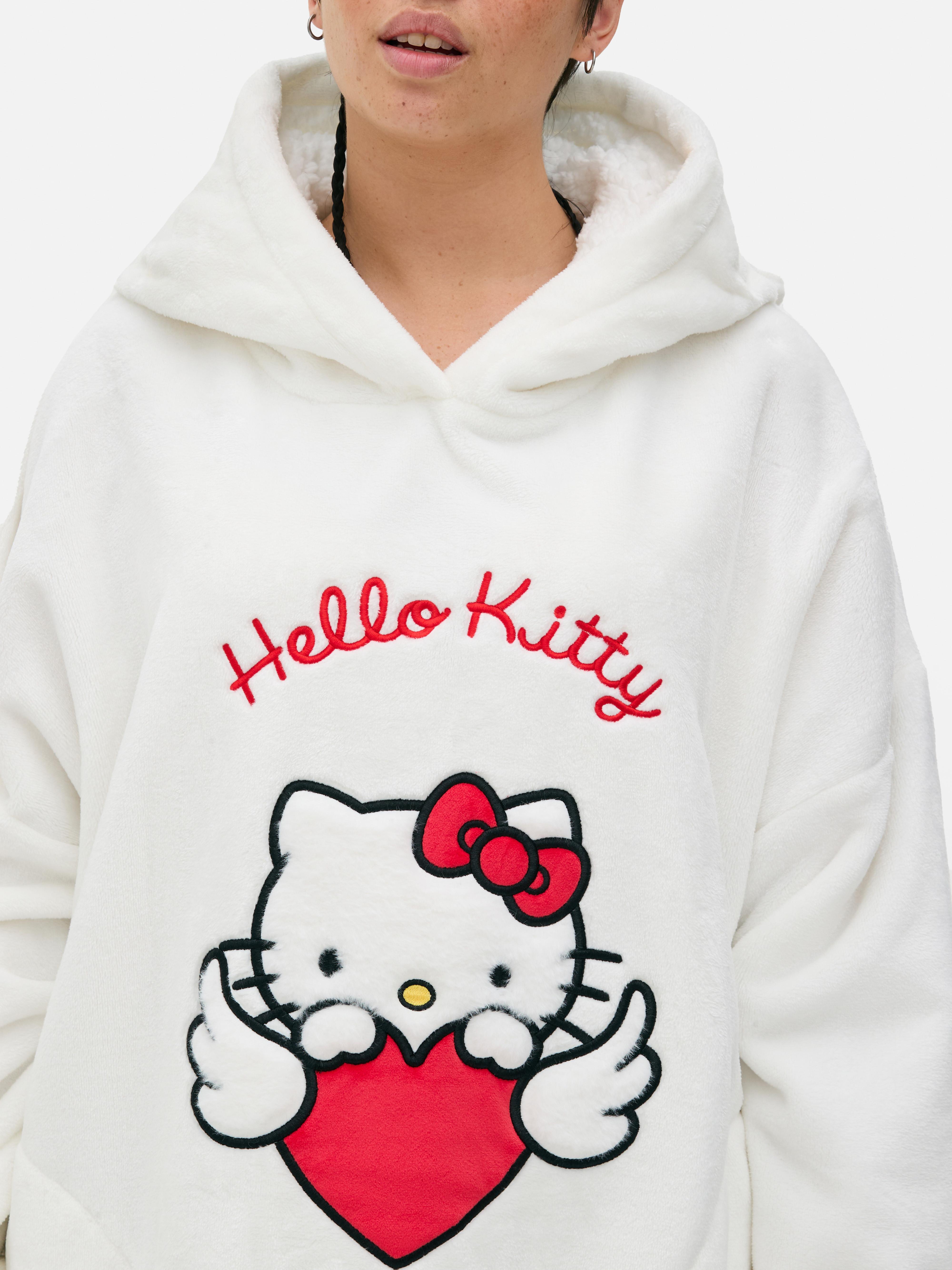 Snuddie Hello Kitty O snuddie Hello Kitty cu glugă, urechi decorative și fundă roșie emblematică