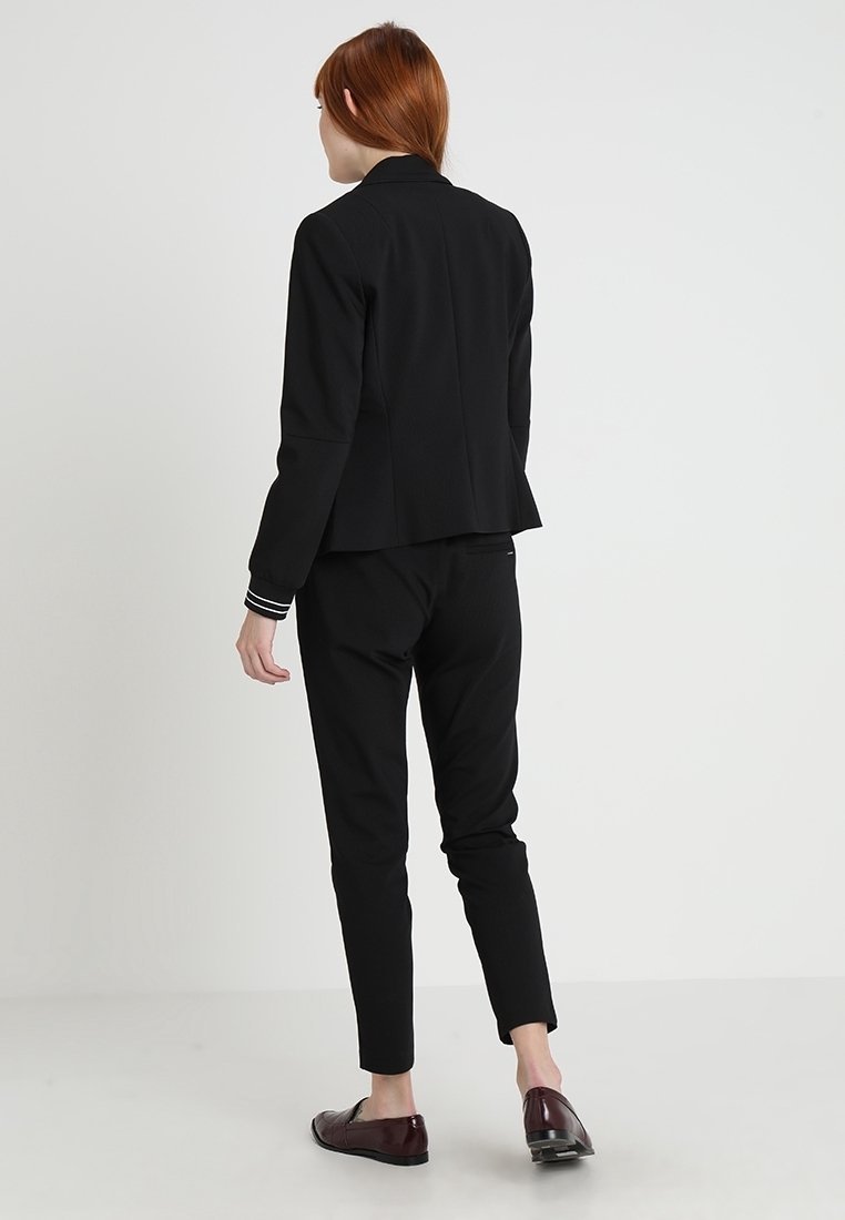Blazer noir à l'identité décontractée.