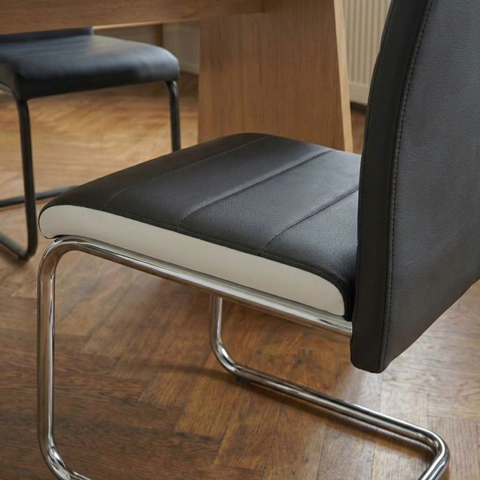 Juego de 2 sillas MARA en piel sintética blanca y negra con patas de metal cromado.