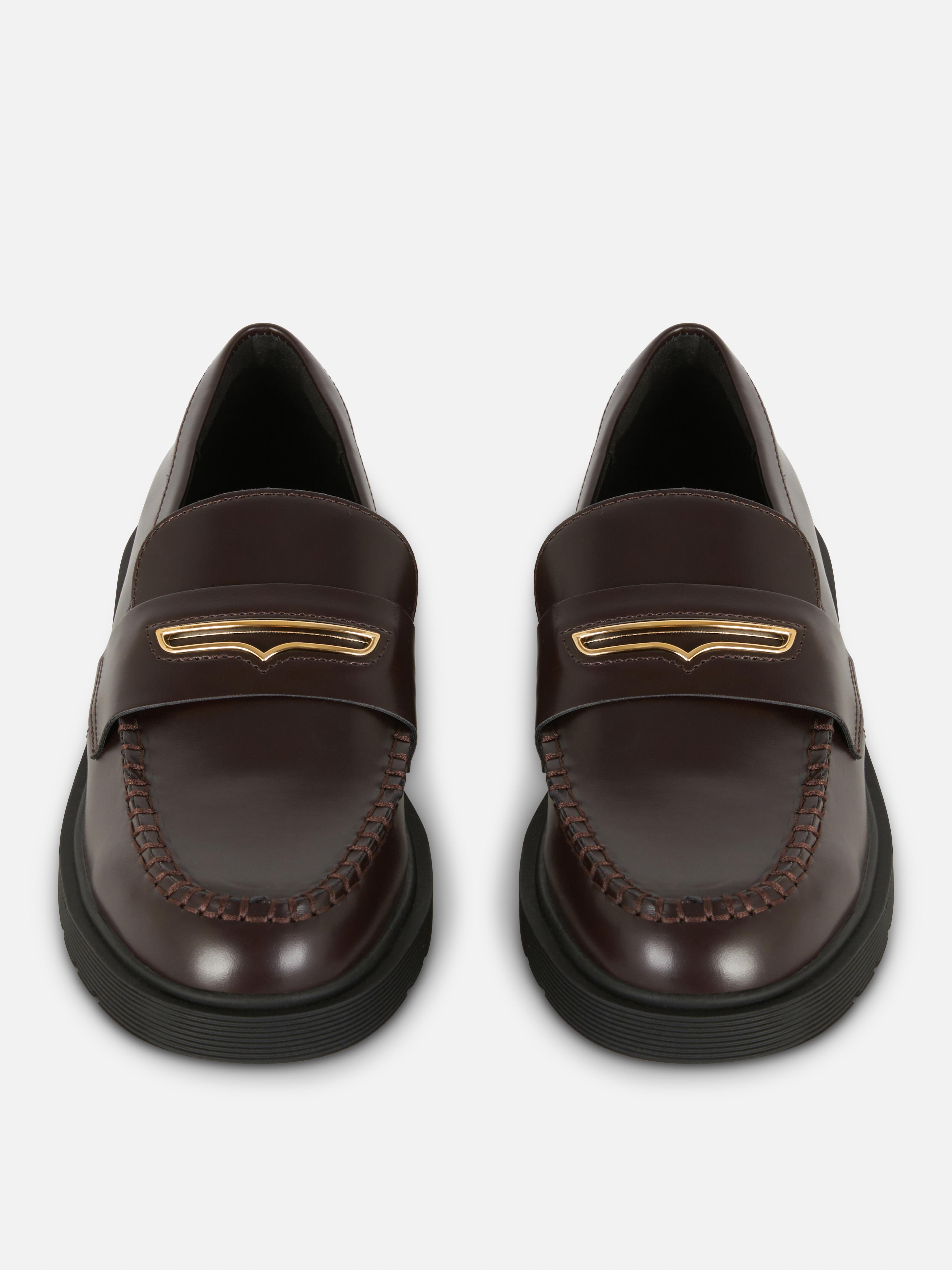 Mocasini lați cu detalii metalice O pereche de mocasini cu o croială largă și decorațiuni metalice în partea de sus