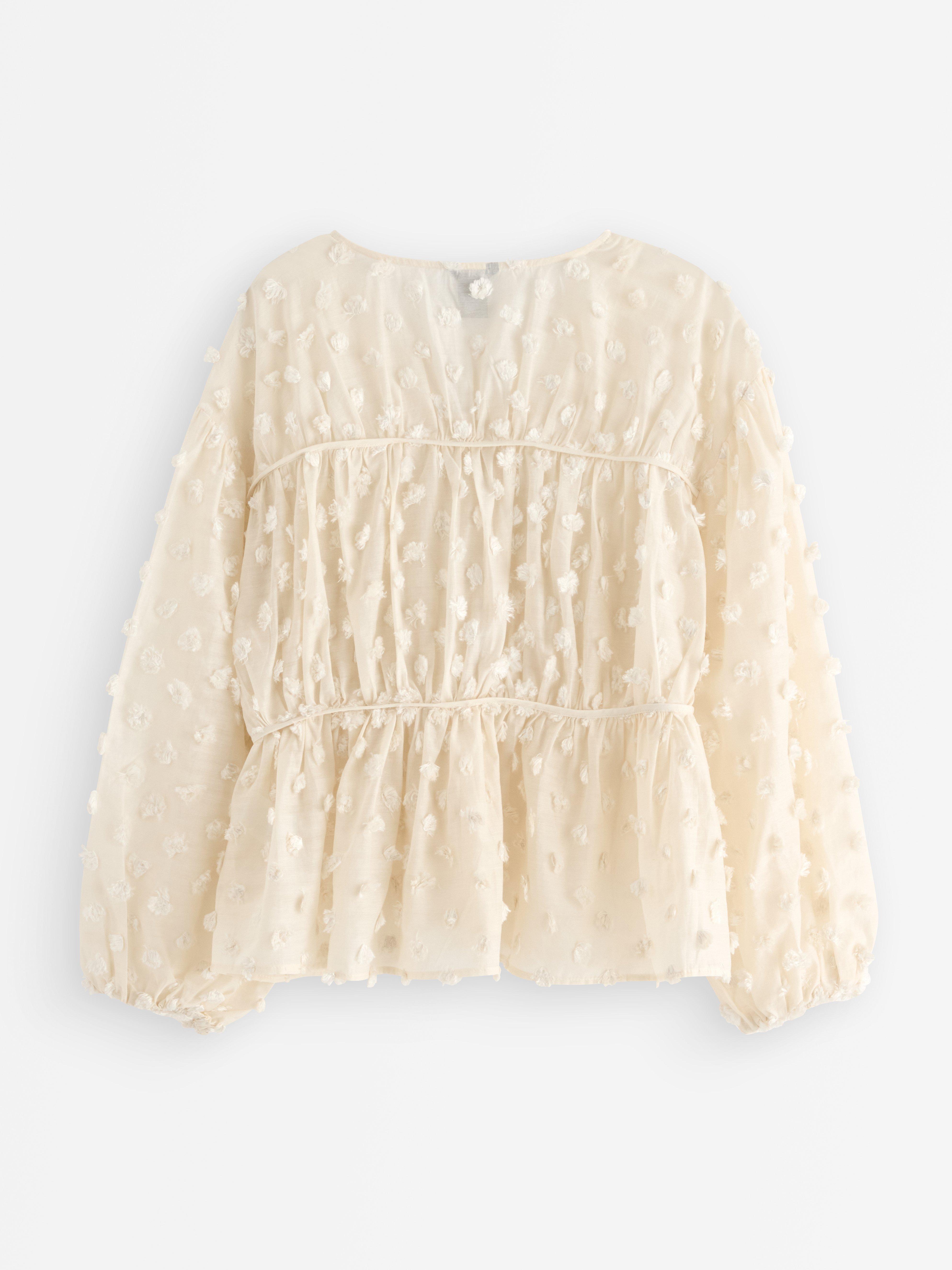 Blusa con lunares esponjosos, color beige claro.