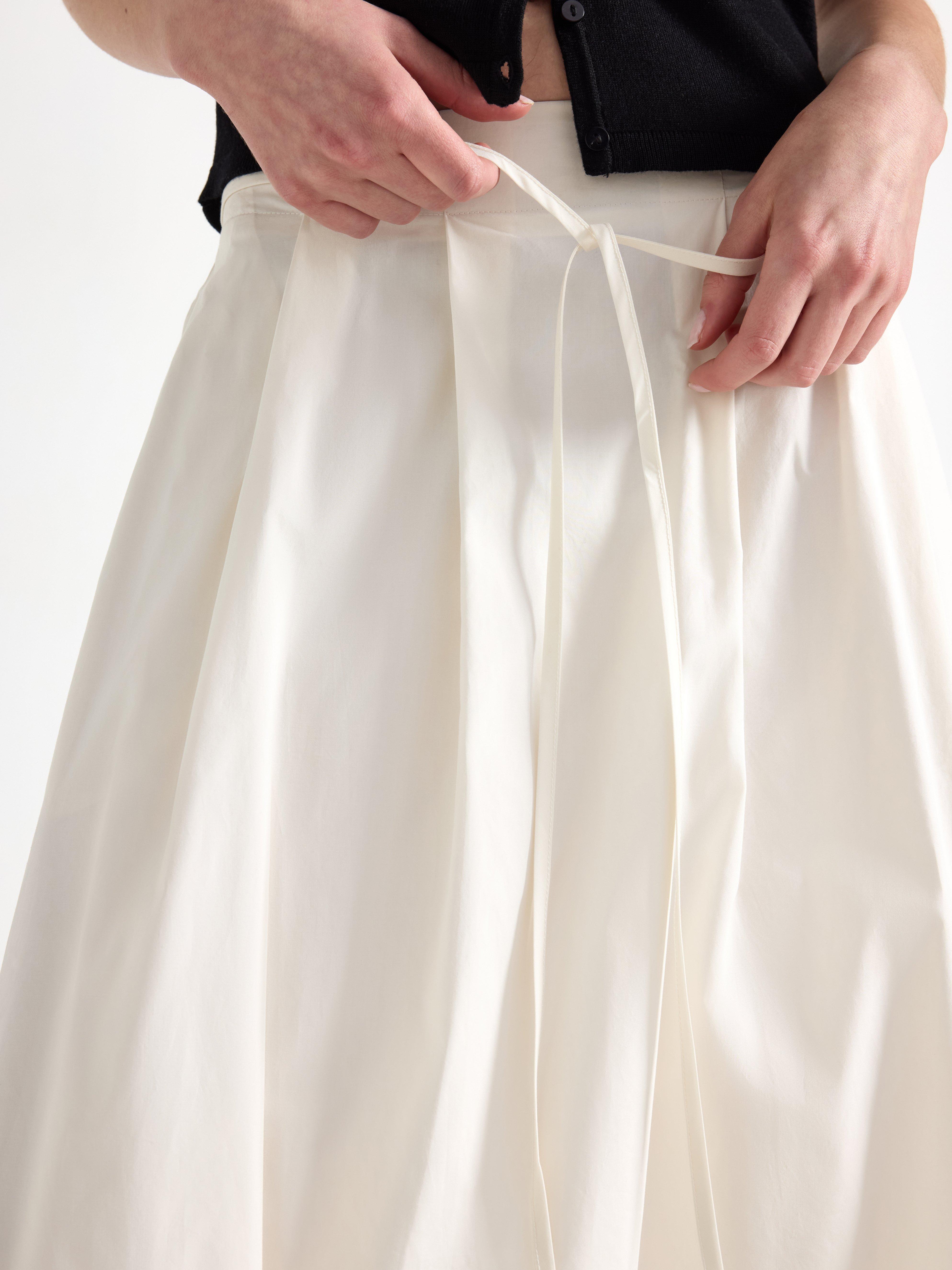 Falda midi plisada, color blanco claro.