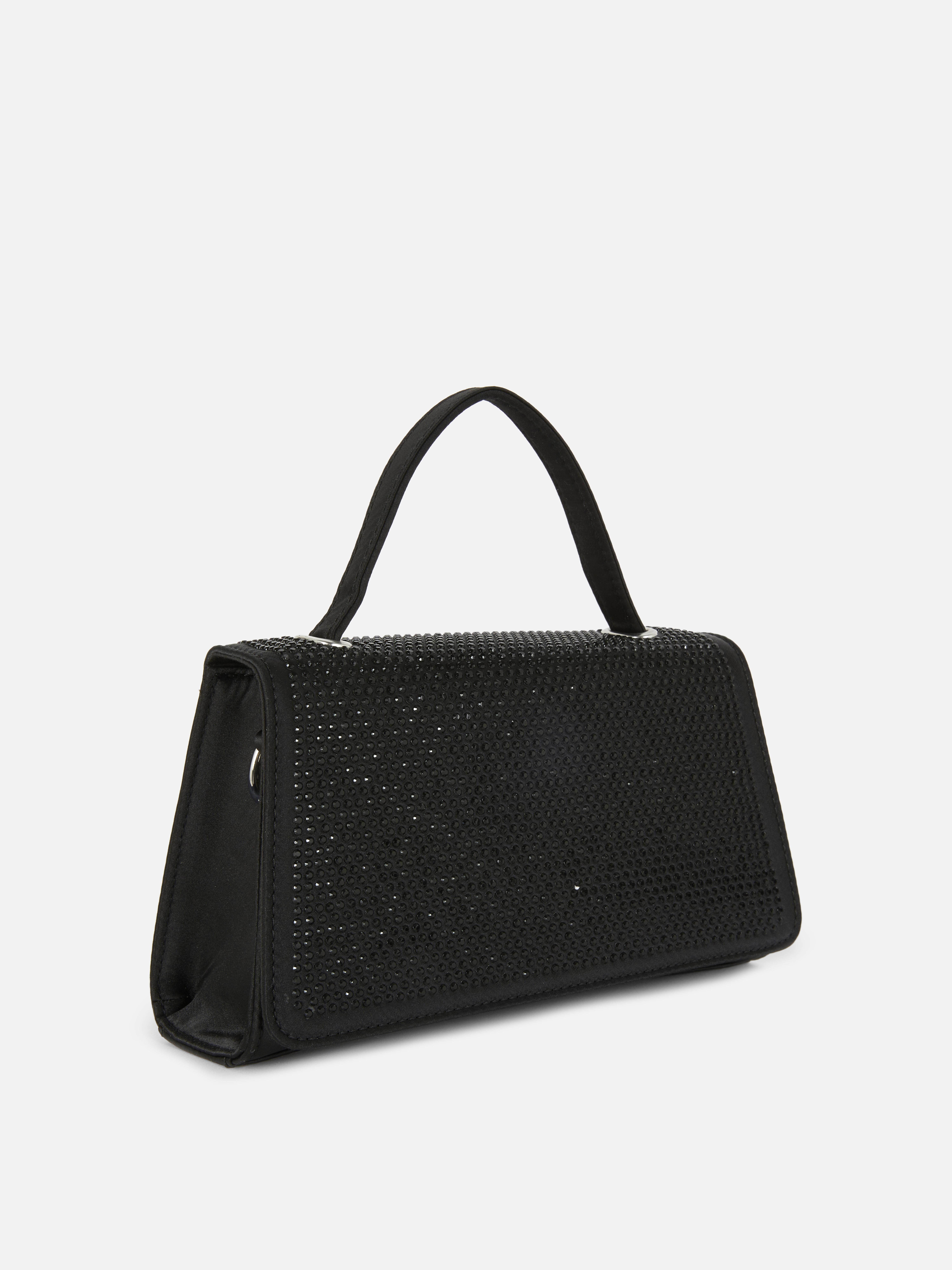 Verzierte Tasche mit Strasssteinen und Henkel. Eine glänzende Tasche mit einem mit Strasssteinen besetzten Henkel.