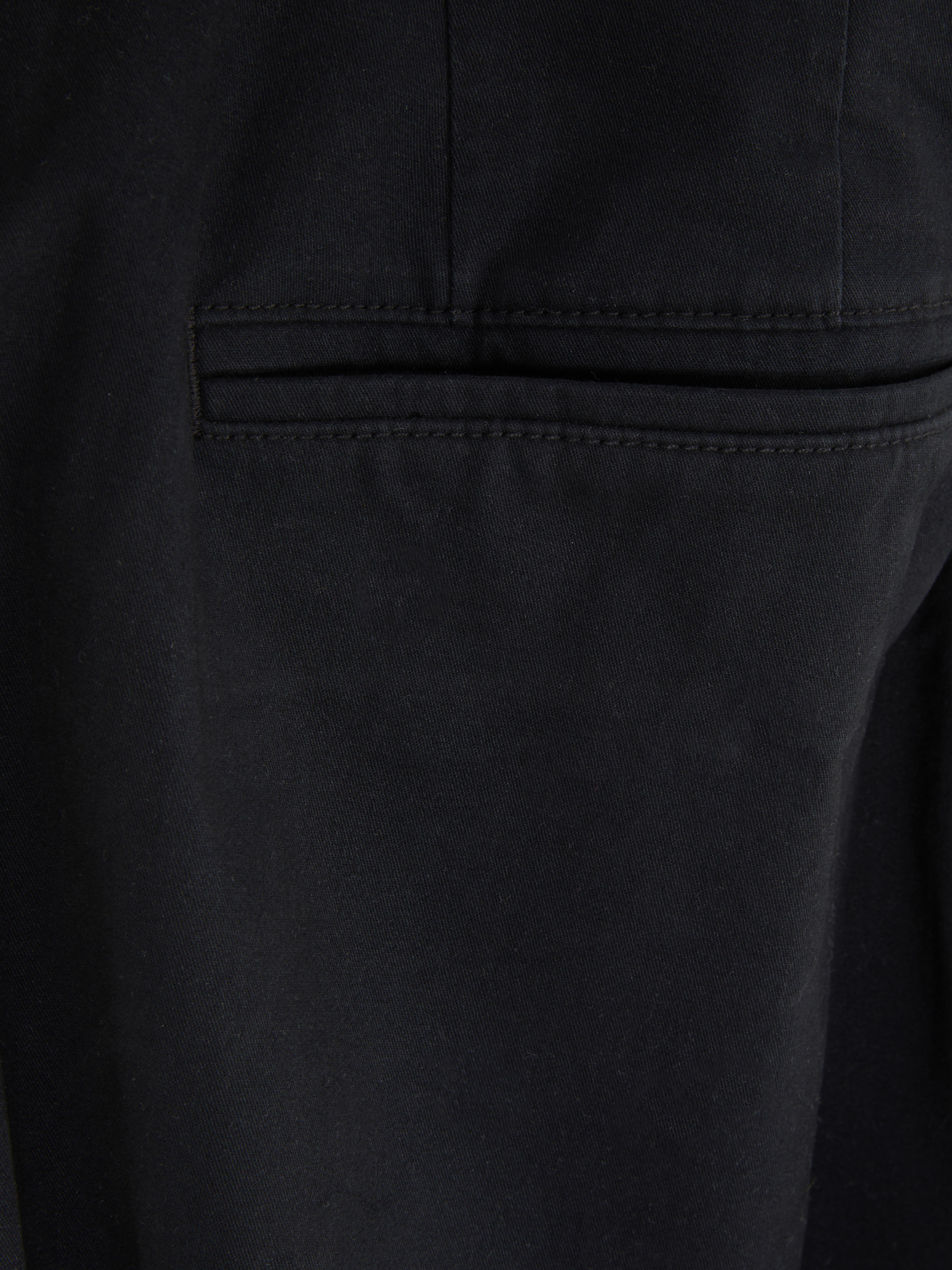 Pantaloni chino elastici, mulați. Pantaloni chino mulați, confecționați în principal din bumbac și cu buzunare laterale.