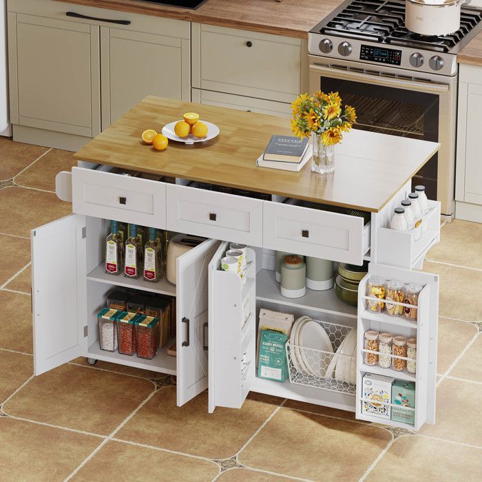 Isla de cocina con 5 ruedas con freno, 4 puertas y 3 cajones. Mesa de comedor con servilletas. Color blanco. Medidas: 140 × 43-70 × 90,5 cm.