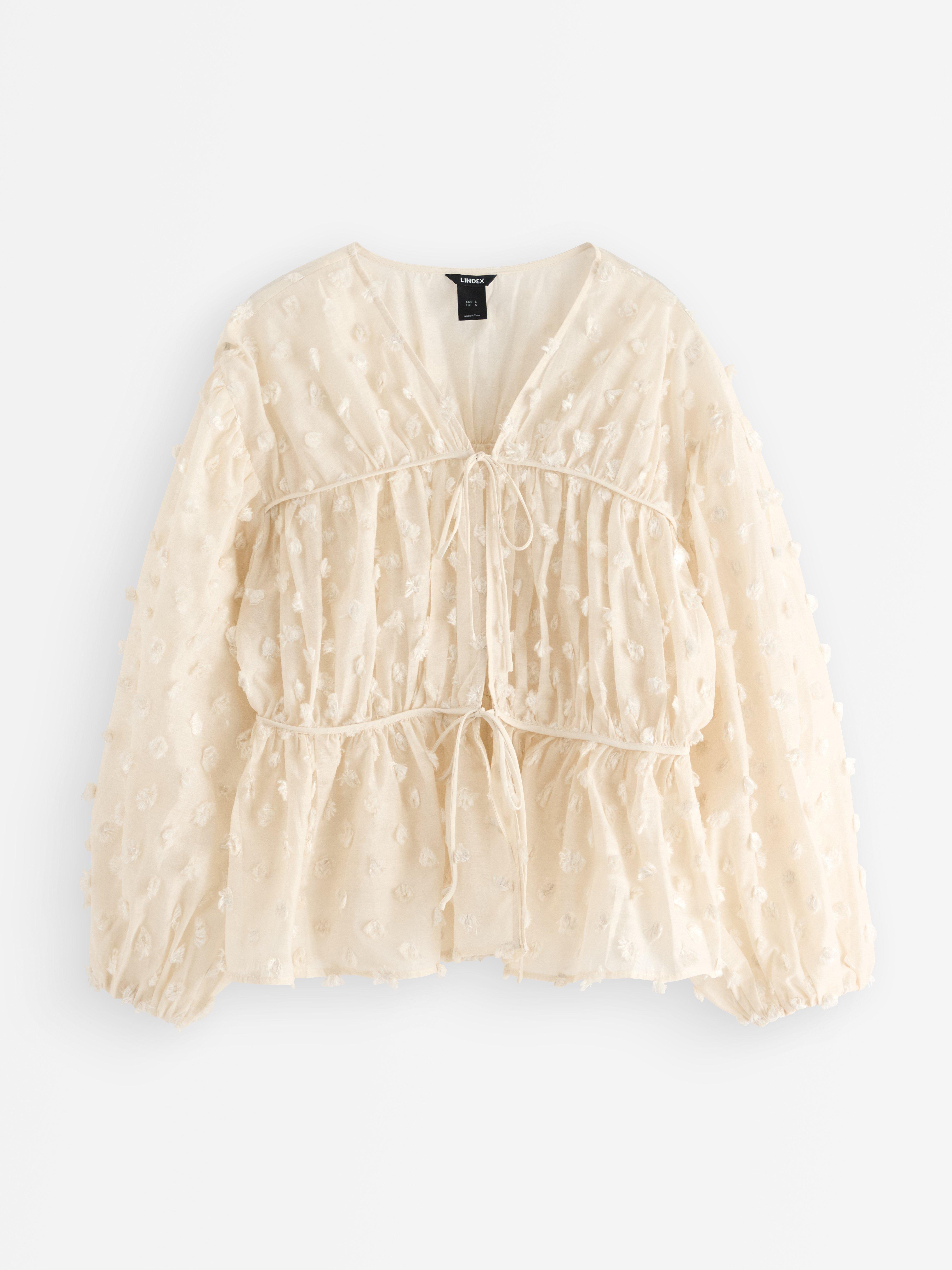 Blusa con lunares esponjosos, color beige claro.
