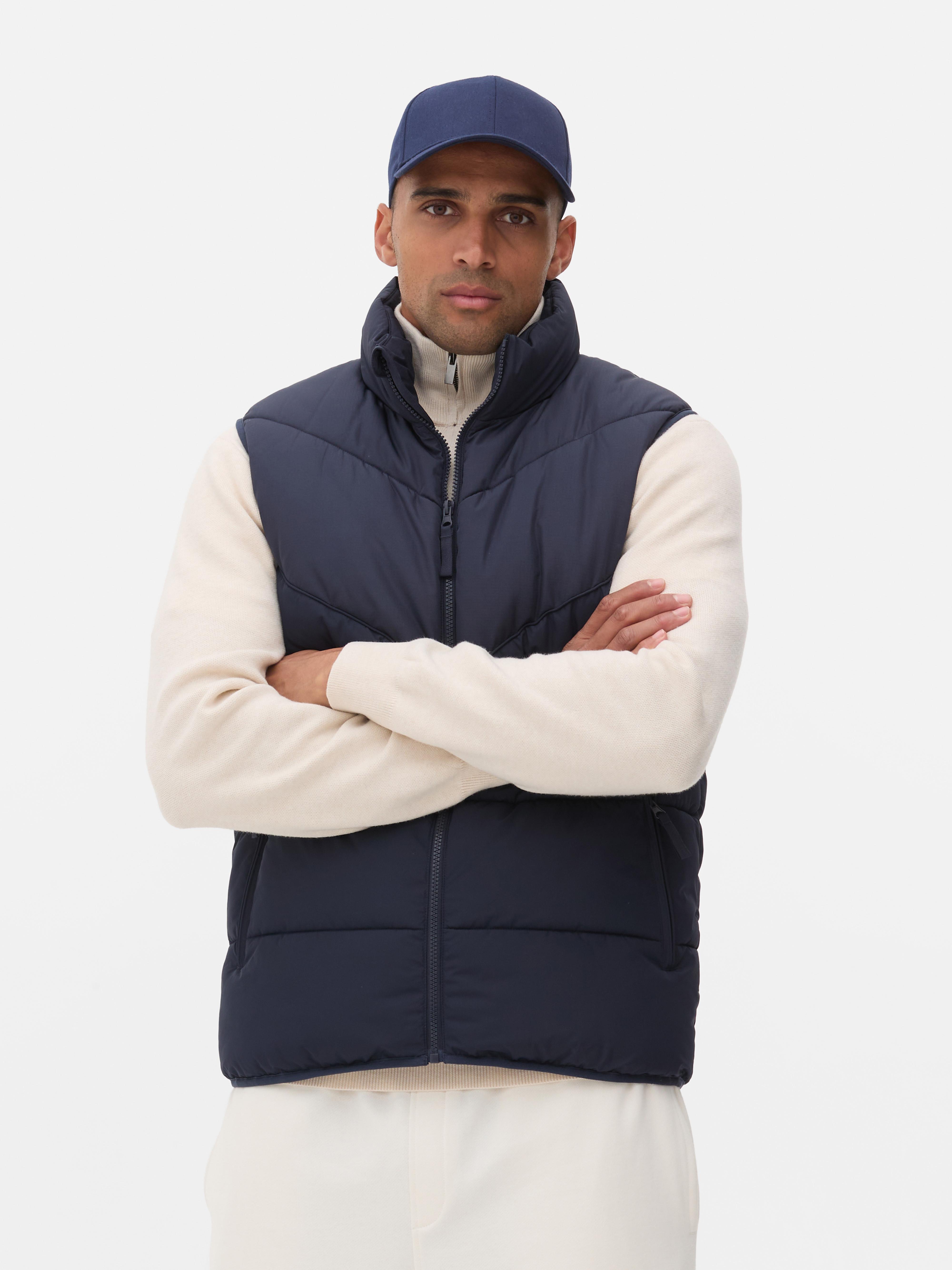 Vestă căptușită cu dungi în zig-zag. O vestă căptușită cu guler ridicat și buzunare multiple pentru sezonul de tranziție.