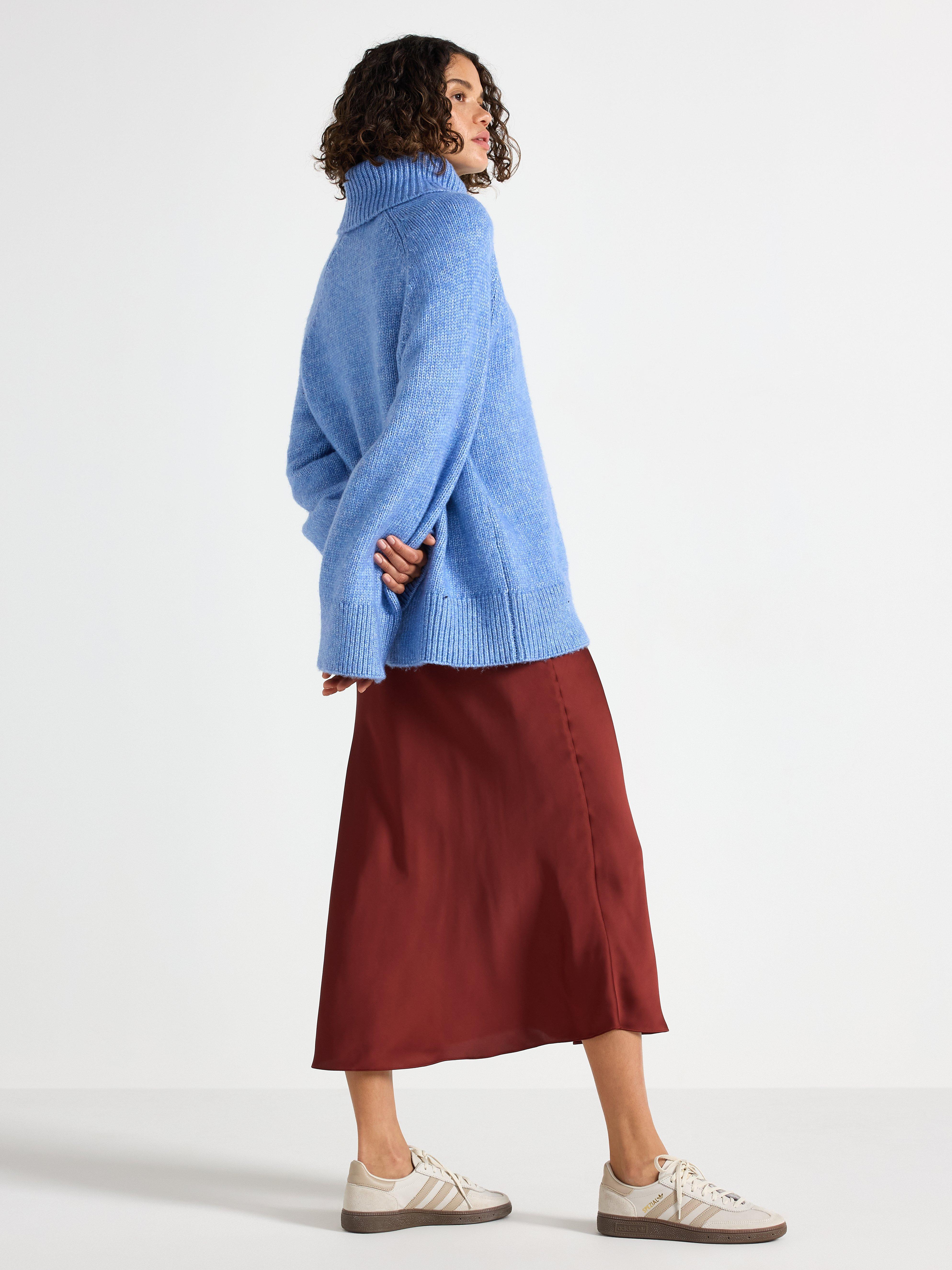 Falda midi de satén color rojo oscuro empolvado.