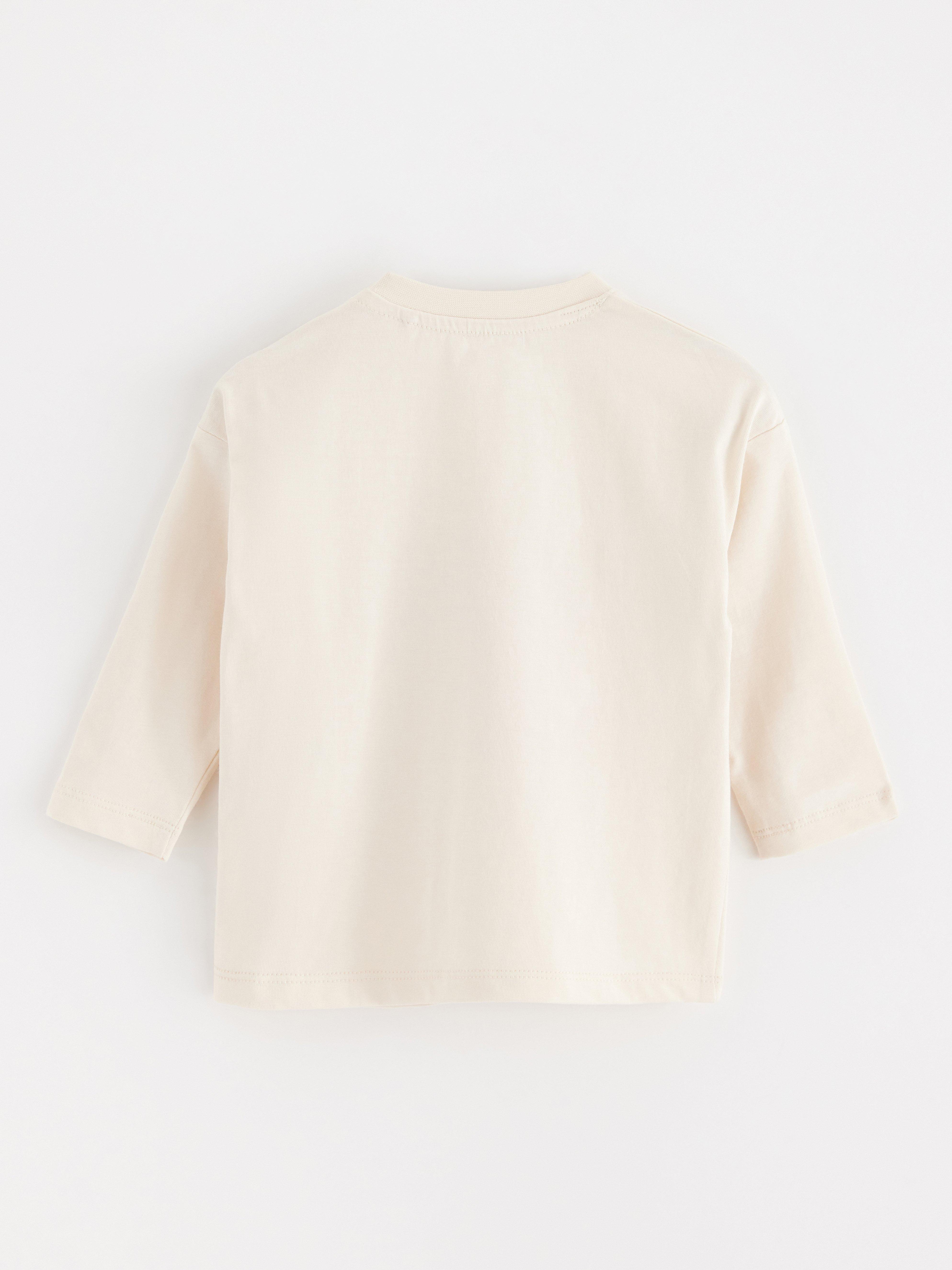Top de manga larga color beige claro.