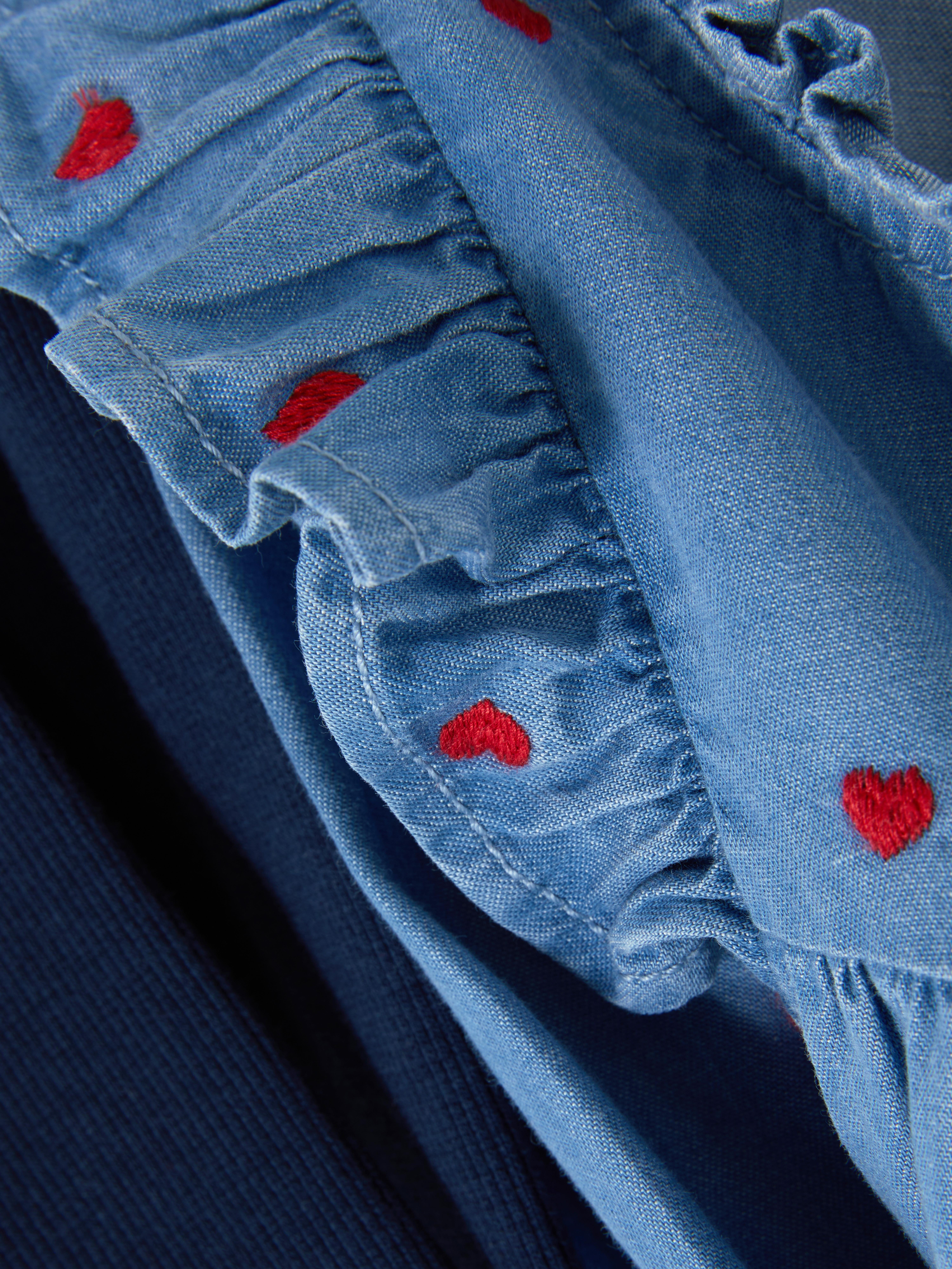 Set format din bluză și colanți din denim cu volane. Un set vestimentar format din o bluză din denim cu volane și colanți elastici.