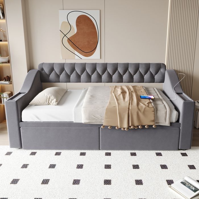 Divano letto trasformabile rivestito in velluto grigio con vano portaoggetti e prese di ricarica.