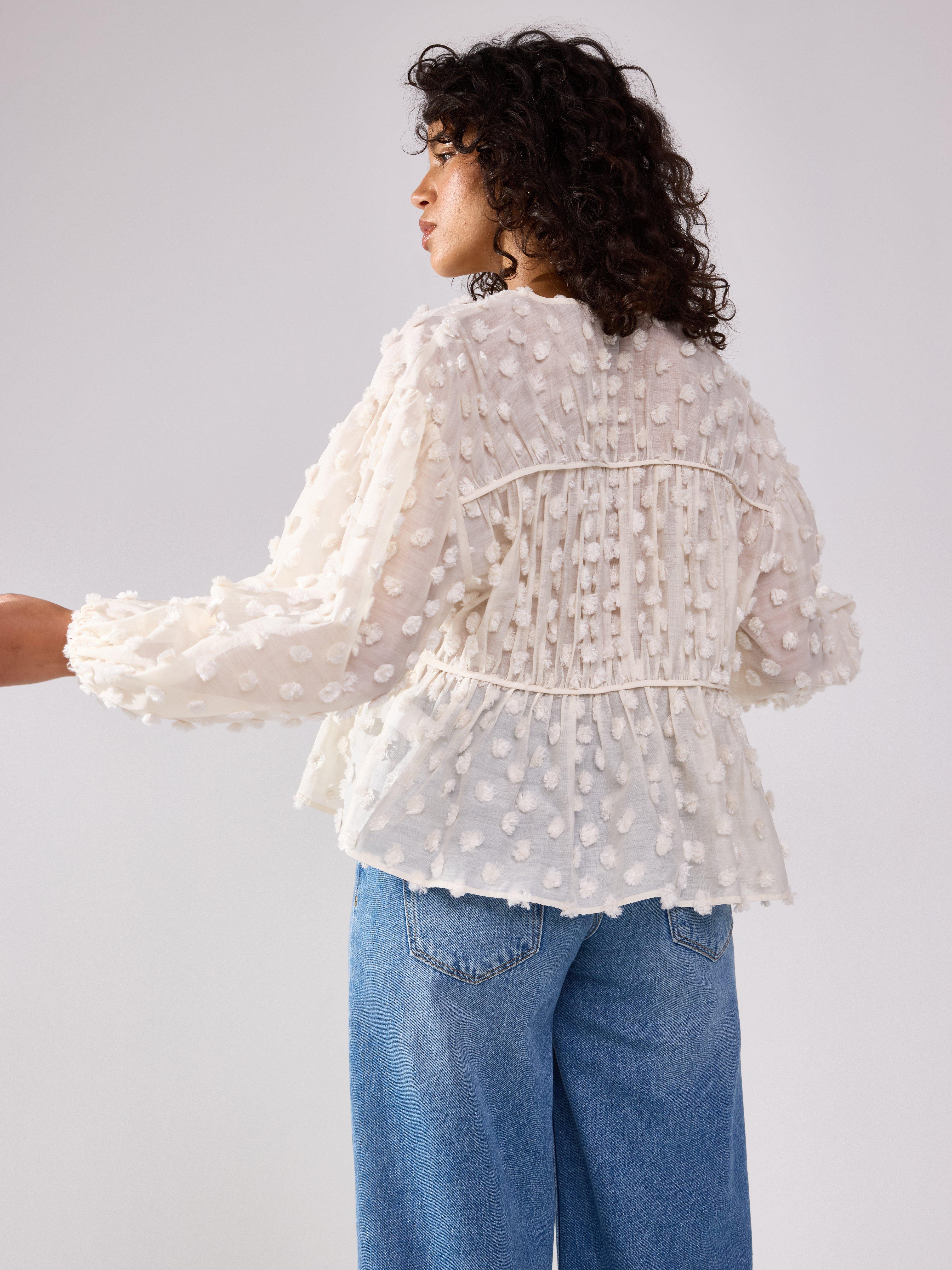 Blusa con lunares esponjosos, color beige claro.