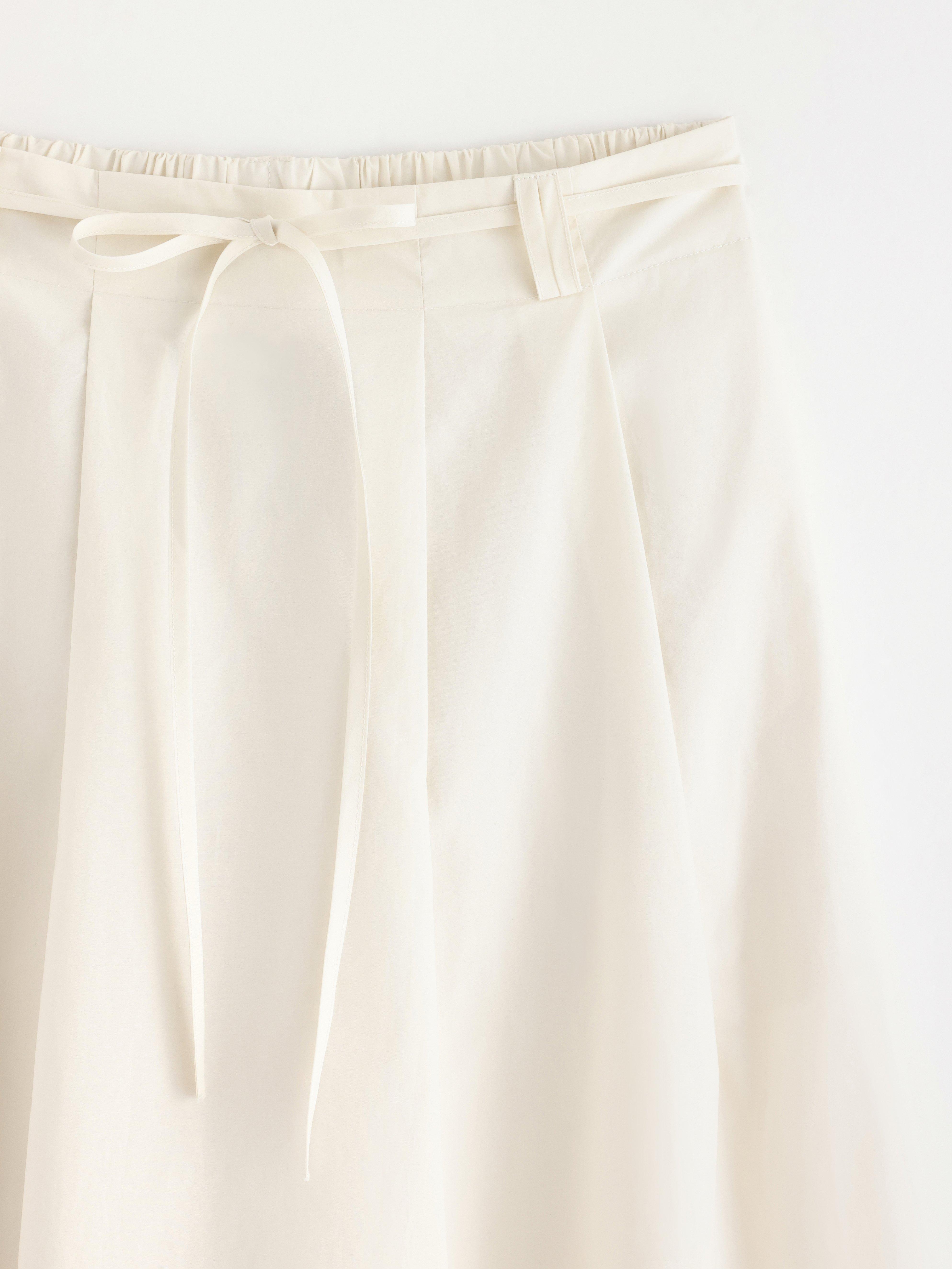 Falda midi plisada, color blanco claro.