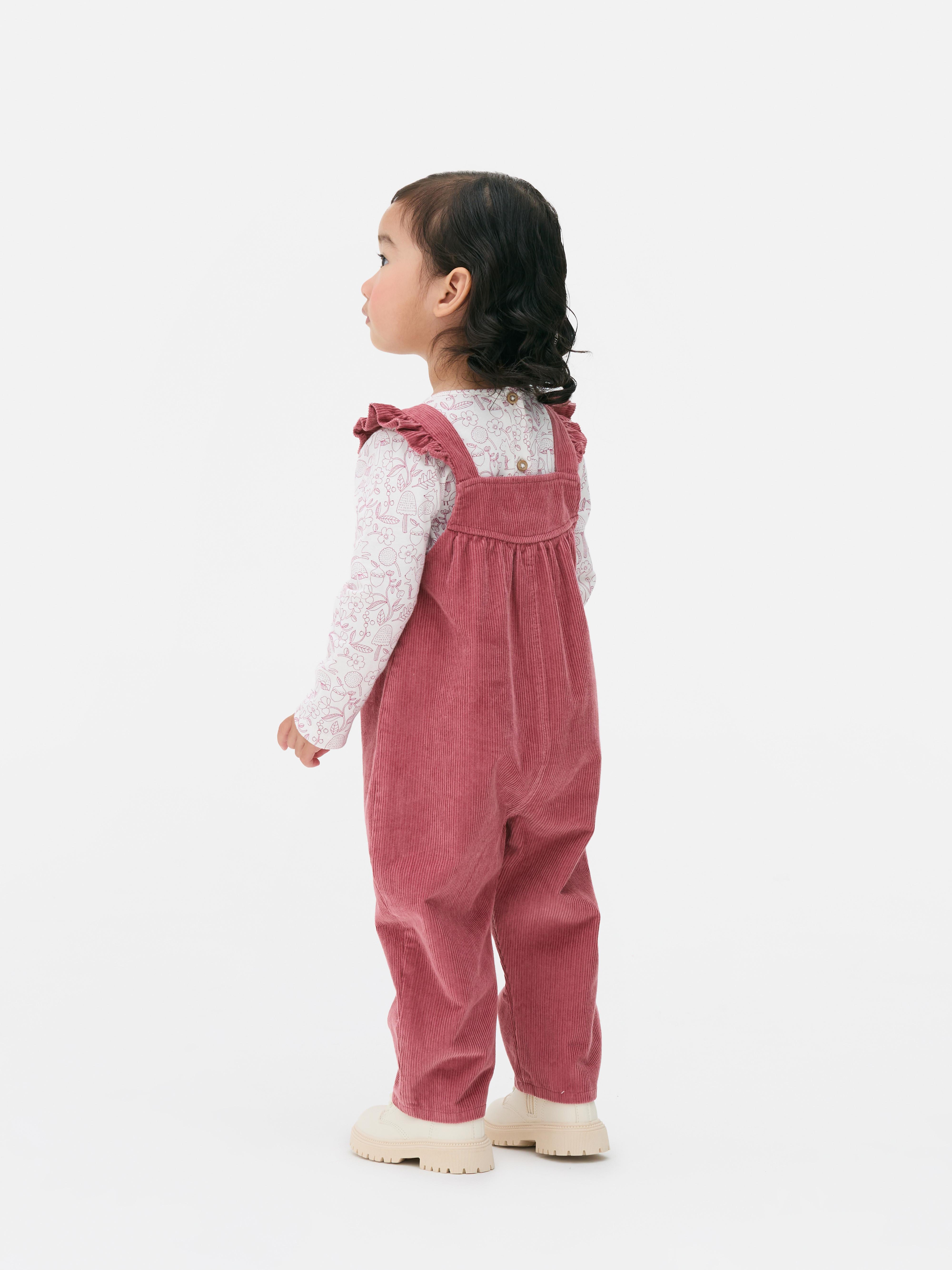 Set format din tricou cu mânecă lungă și salopetă. Un tricou cu mânecă lungă cu model și salopetă din catifea reiată.