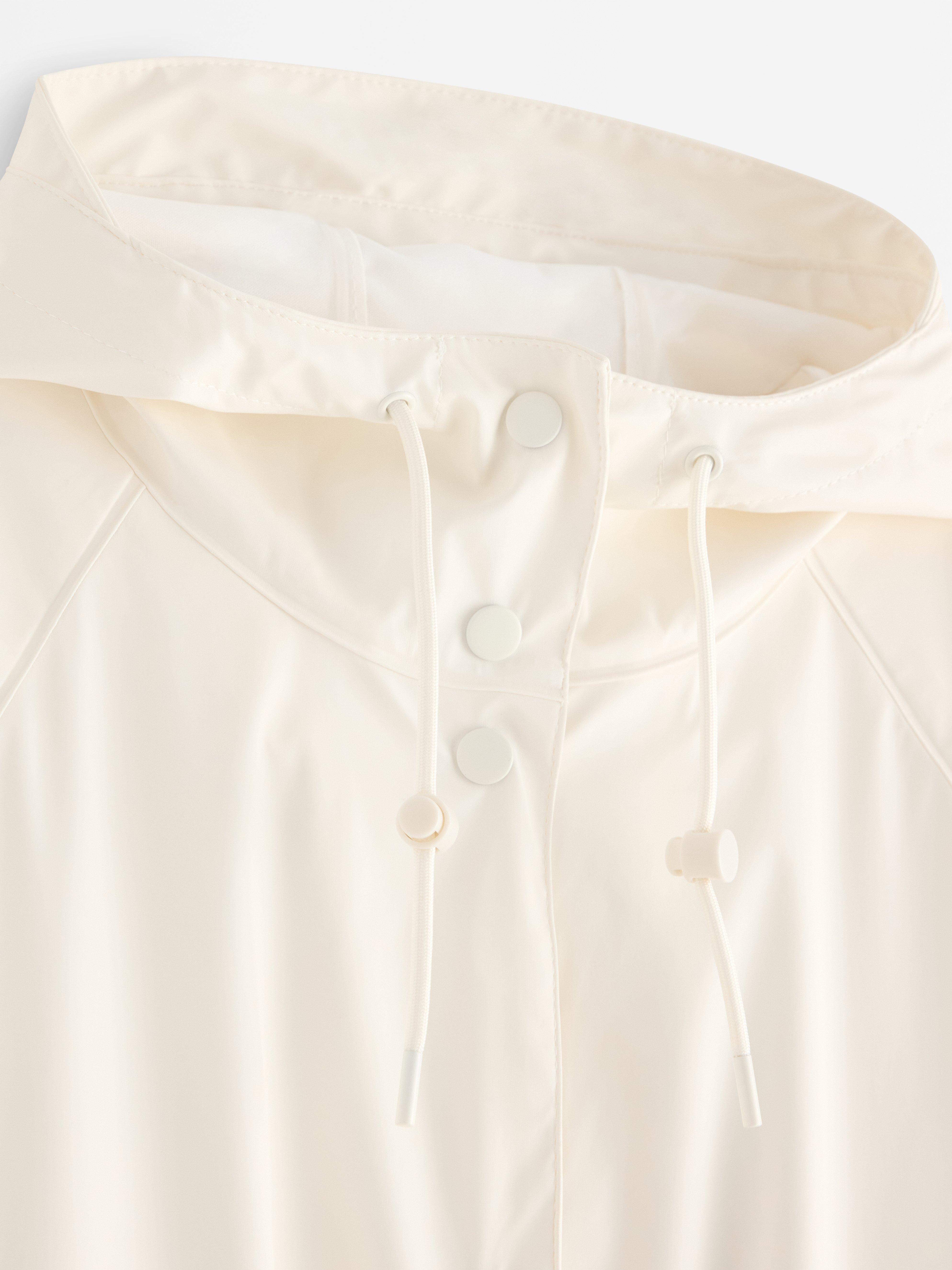 Chaqueta impermeable con capucha color blanco roto.