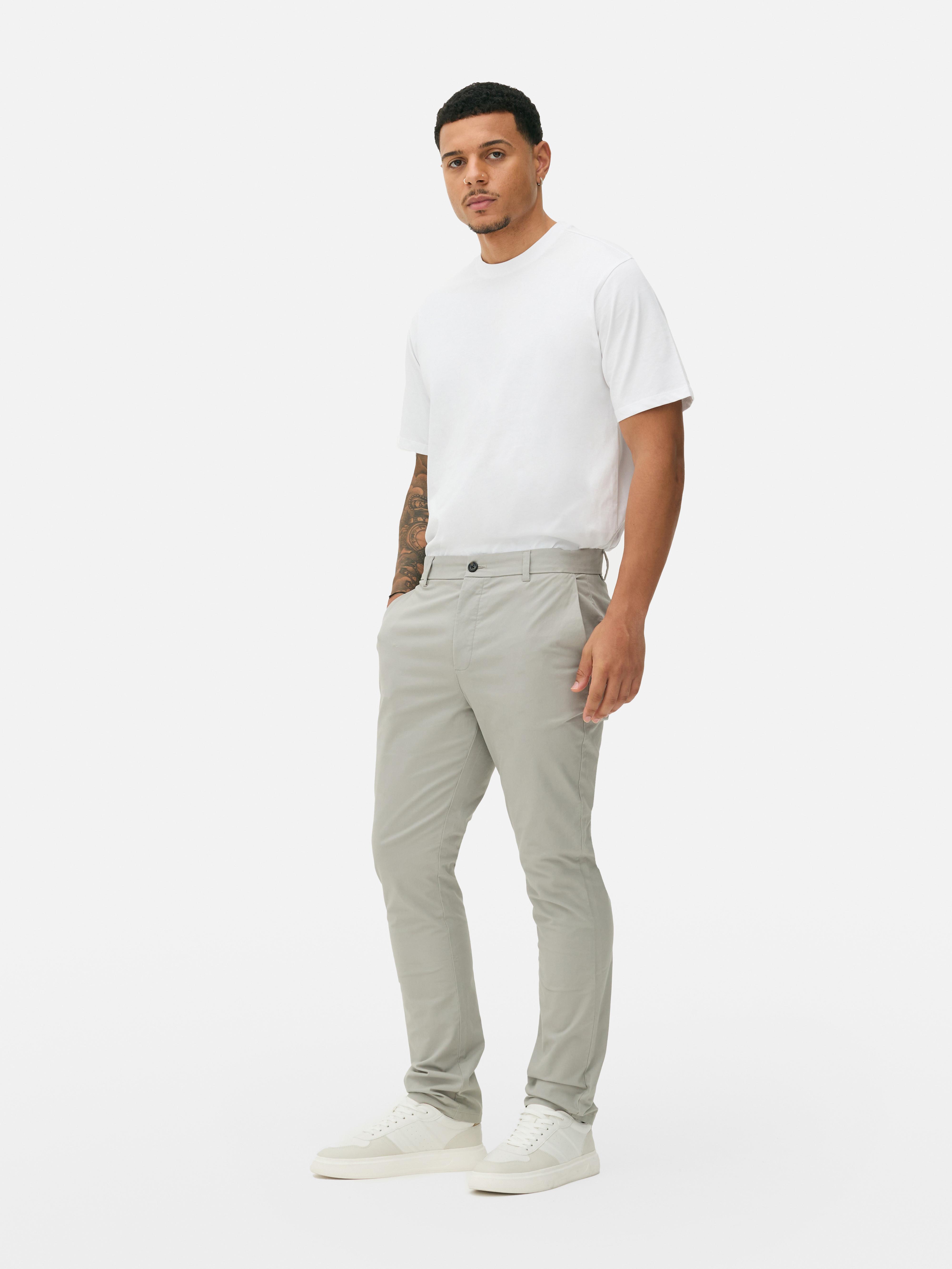 Pantaloni chino elastici, mulați. Pantaloni chino mulați, confecționați în principal din bumbac și cu buzunare laterale.