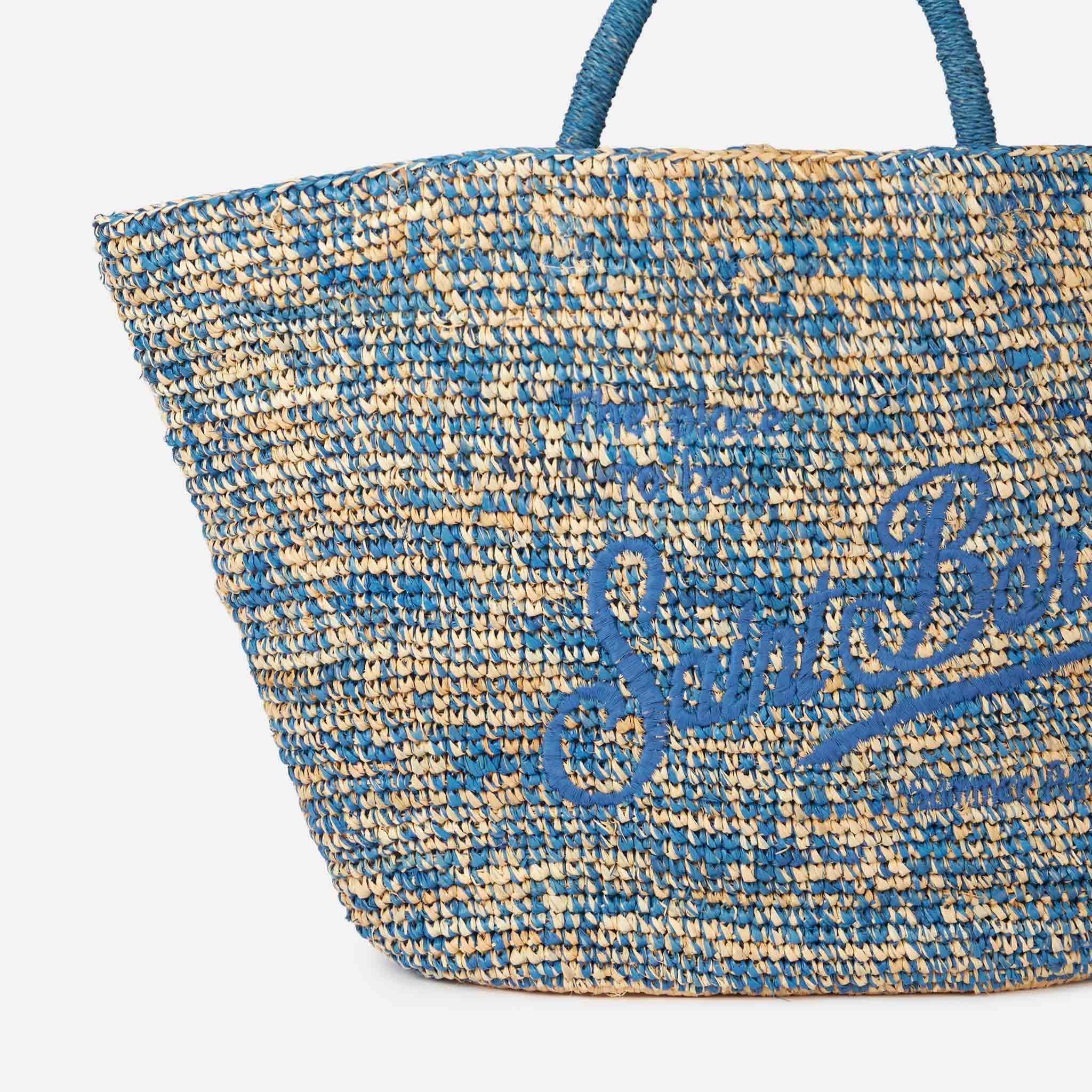 Blauw-witte raffia tas met borduurwerk aan de voorkant.