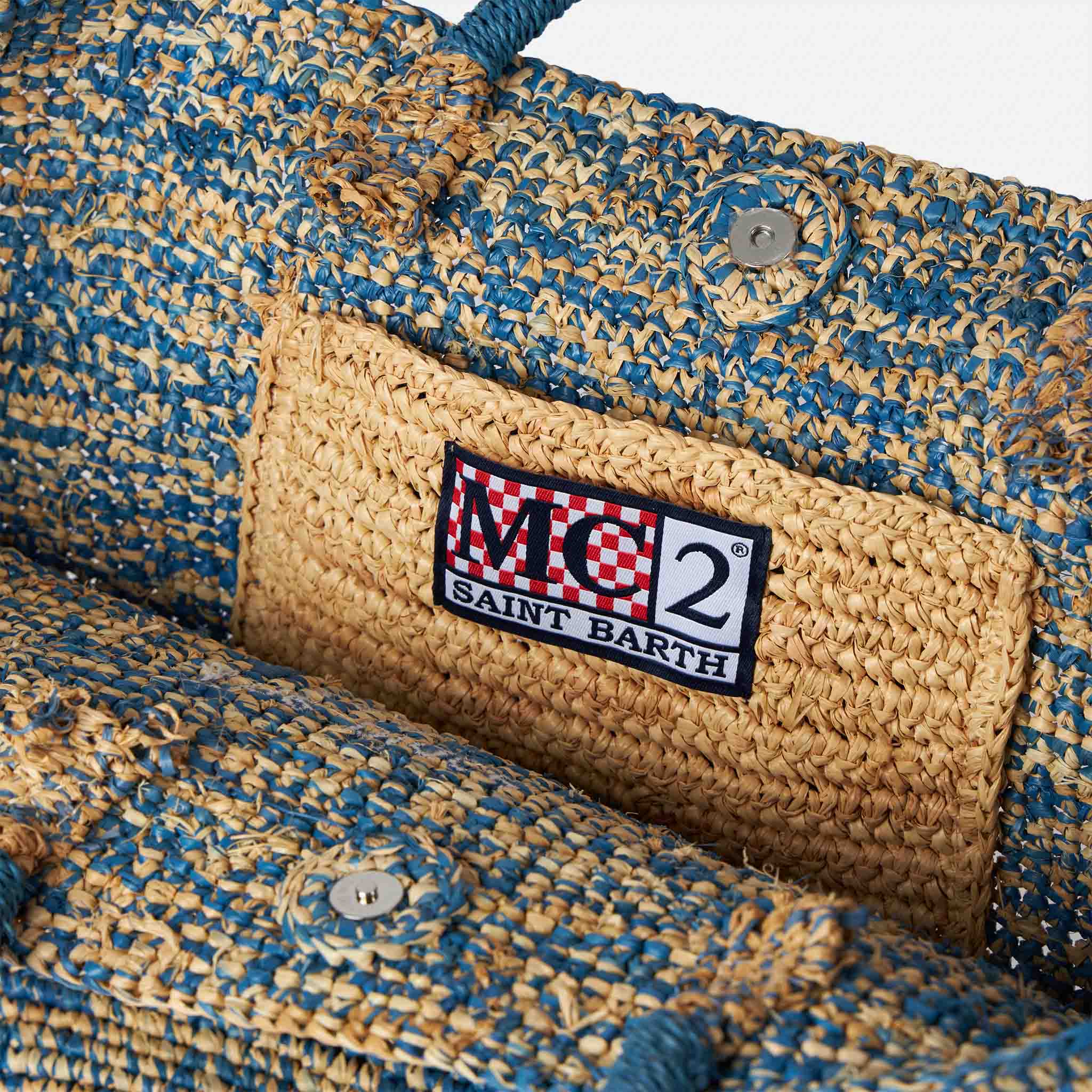 Blauw-witte raffia tas met borduurwerk aan de voorkant.