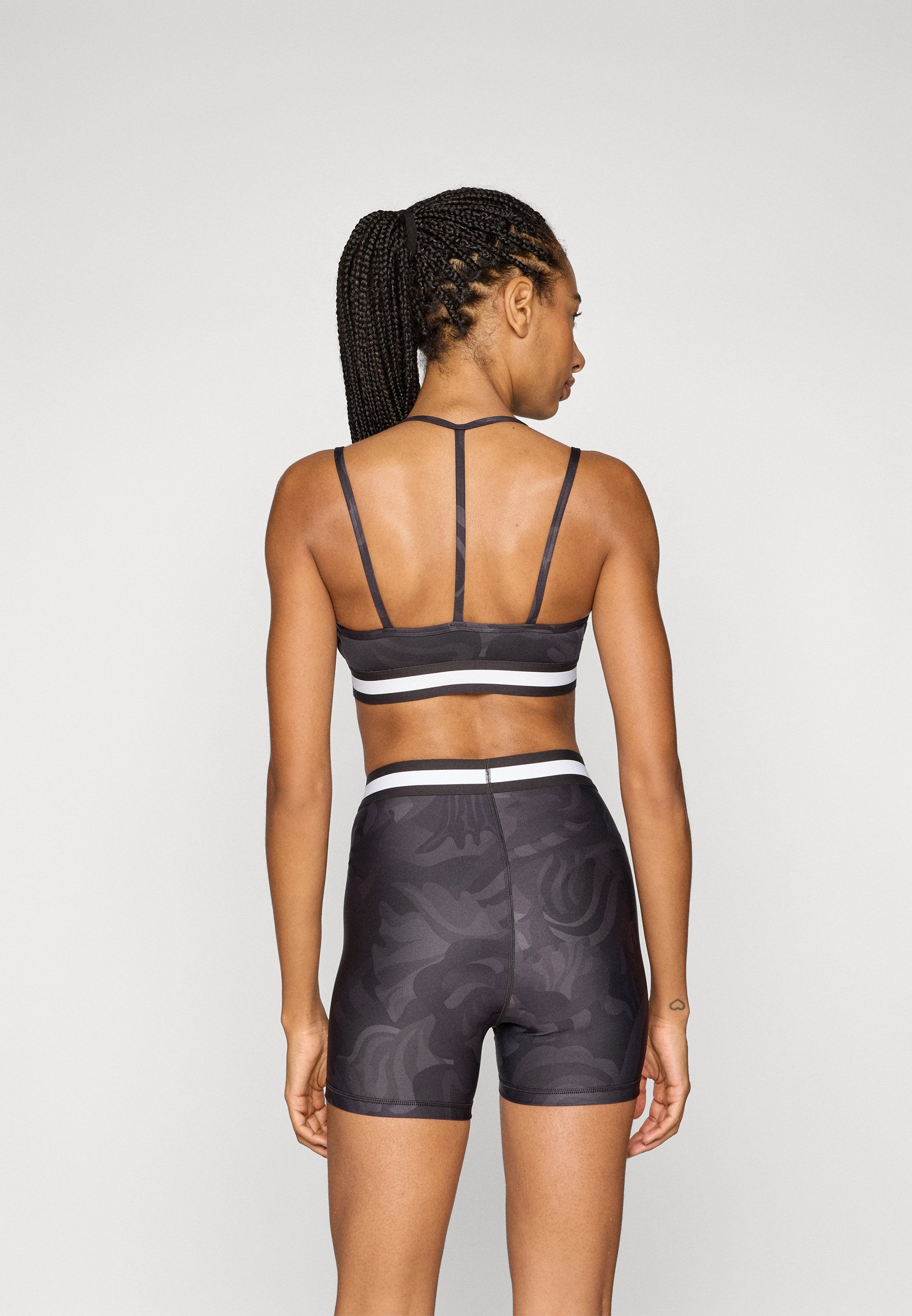 Soutien-gorge de sport à bretelles fines et à ruban floral Puma - Maintien léger - Noir