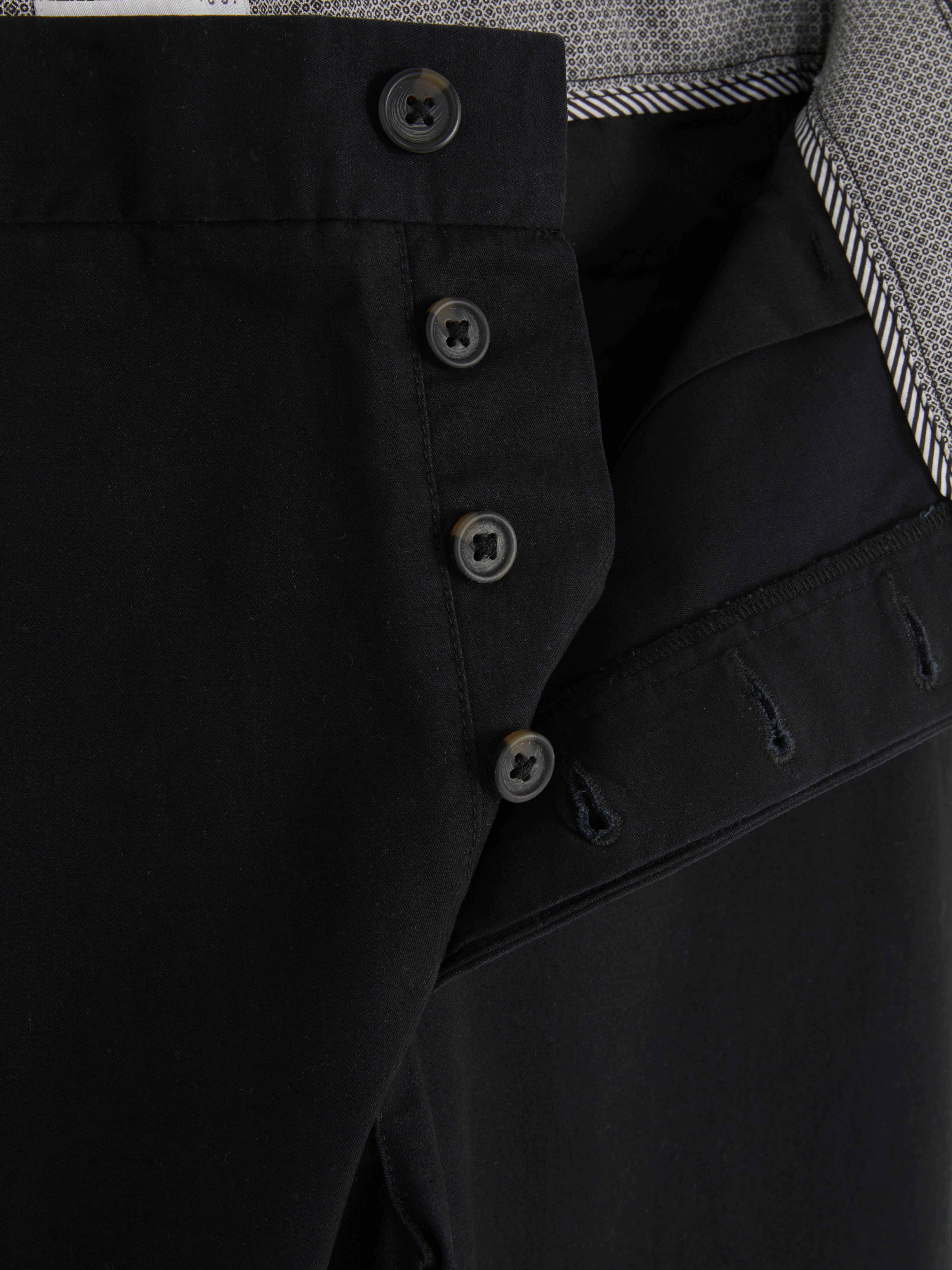Pantaloni chino elastici, mulați. Pantaloni chino mulați, confecționați în principal din bumbac și cu buzunare laterale.