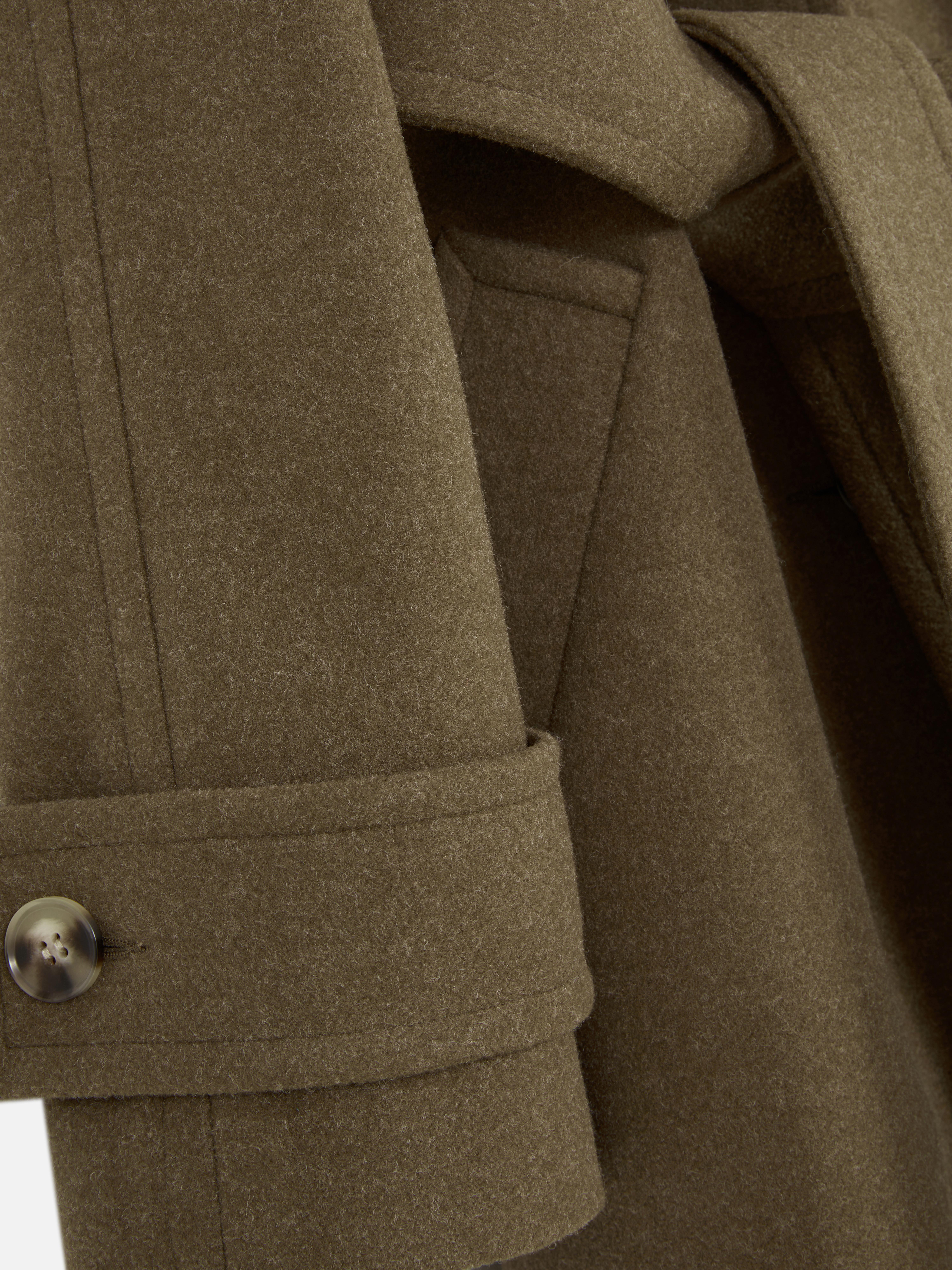 Takki pystykauluksella Pitkä takki pystykauluksella, solmittavalla vyöllä ja taskuilla