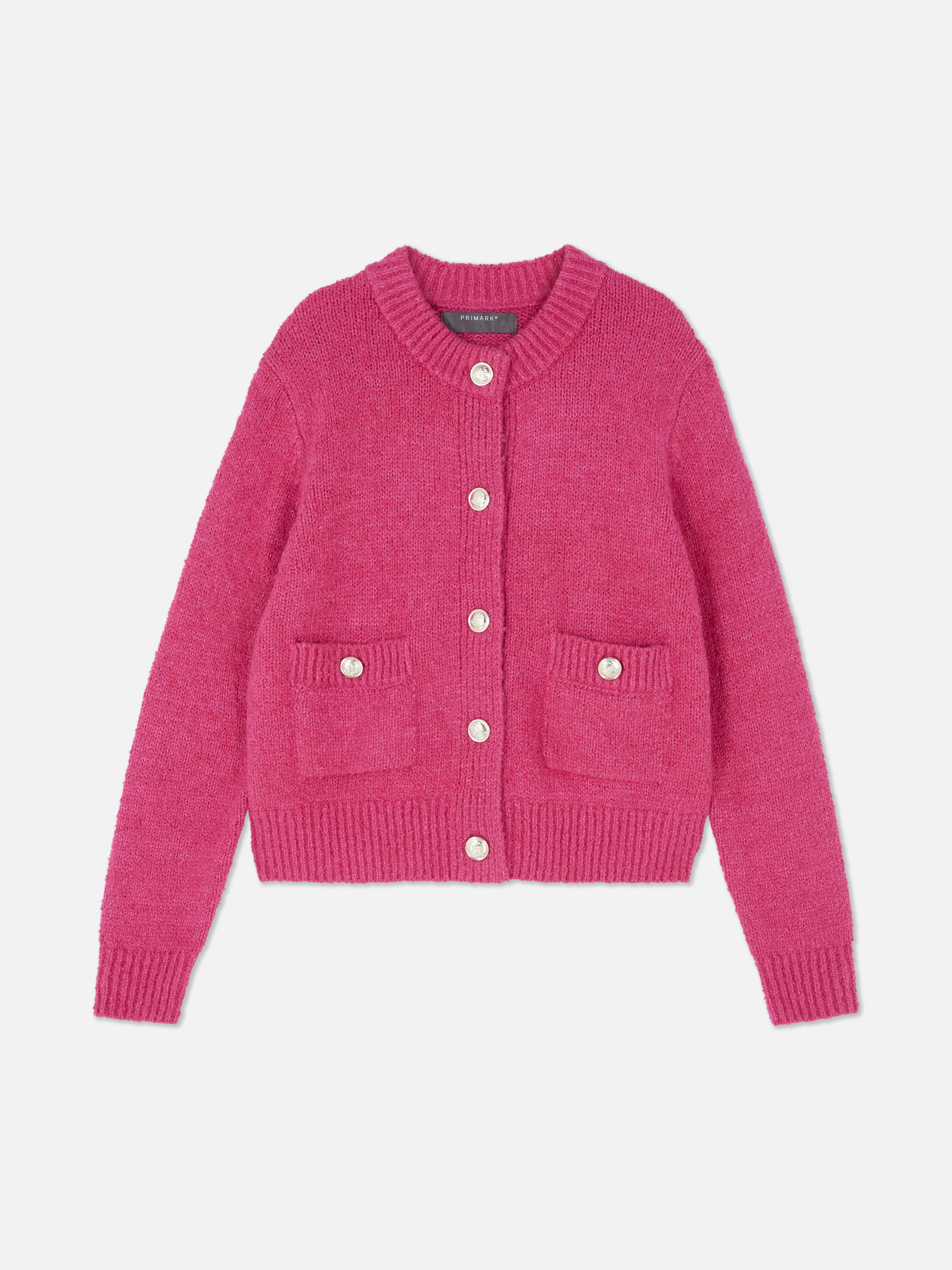 Bouclé-Strickjacke mit Knopfverschluss. Eine Strickjacke aus Bouclé-Stoff mit gerippten Bündchen, Knöpfen und aufgesetzten Taschen.