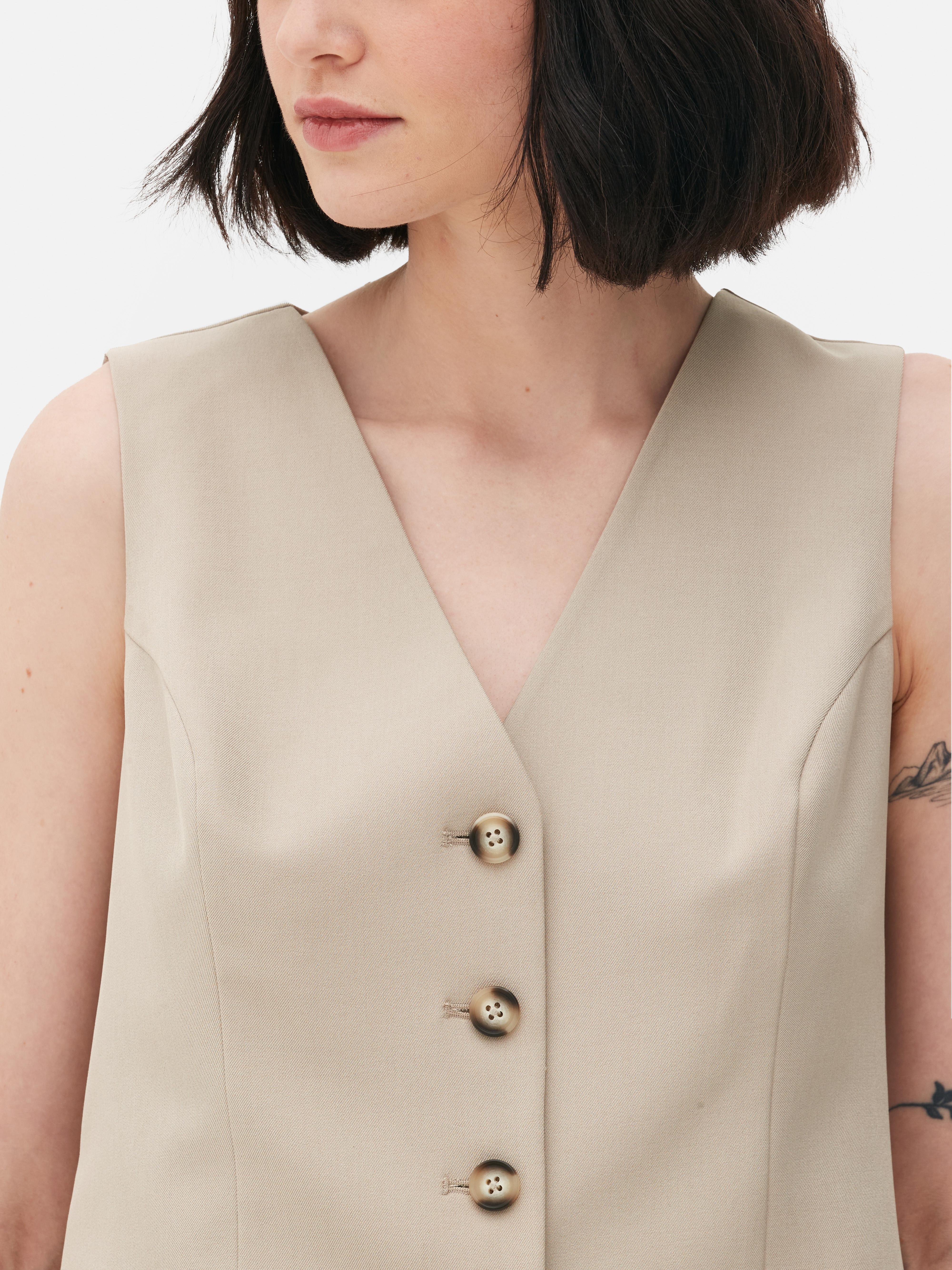 Vestă elegantă cu închidere cu nasturi. Această vestă atemporală, cu cusături prințesă, închidere cu nasturi și decolteu în V, este un adevărat must-have.