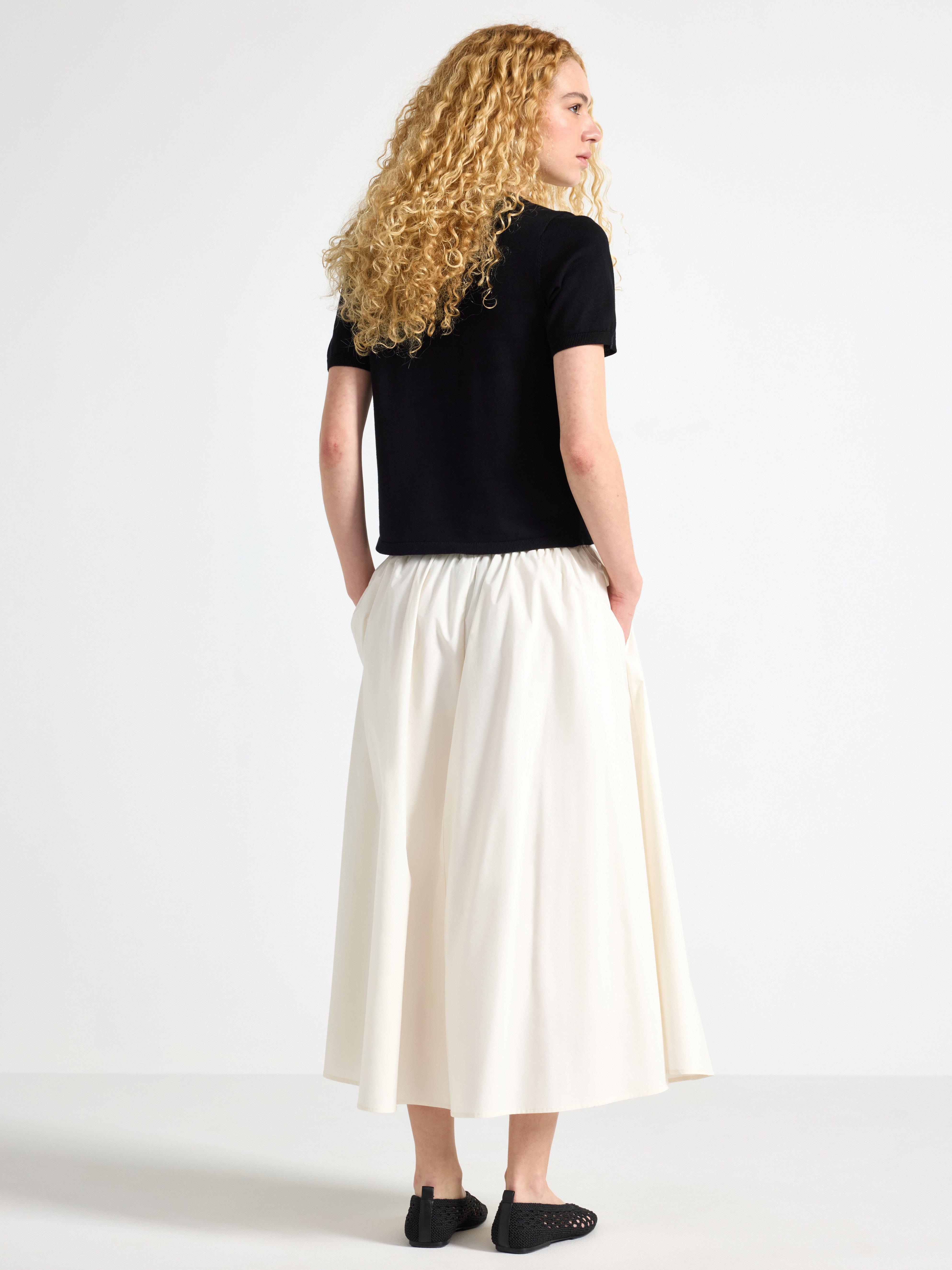 Falda midi plisada, color blanco claro.